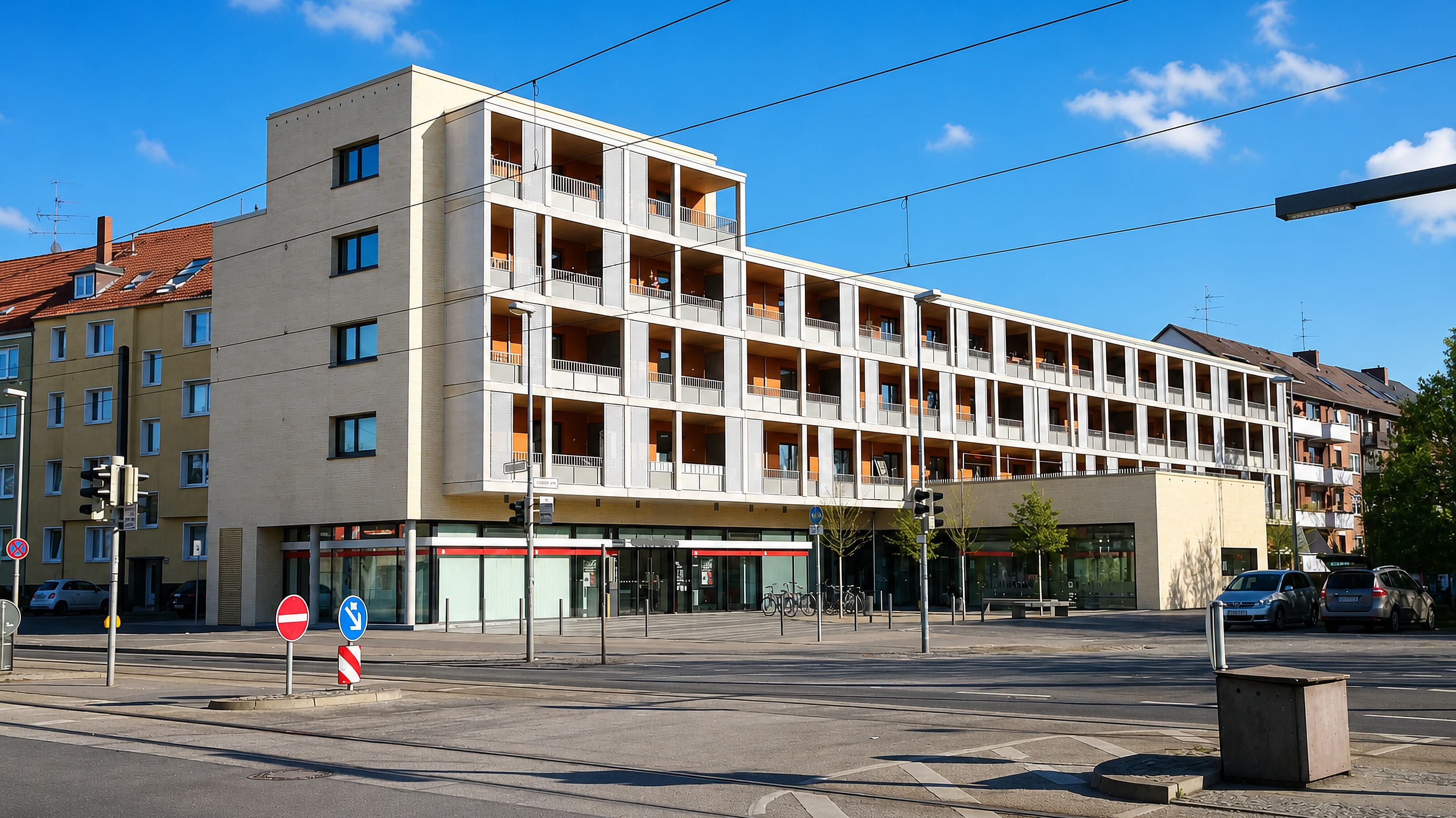 Modern corner apartment block with ground-floor shops on a tram-lined street in Hainholz, Hannover.