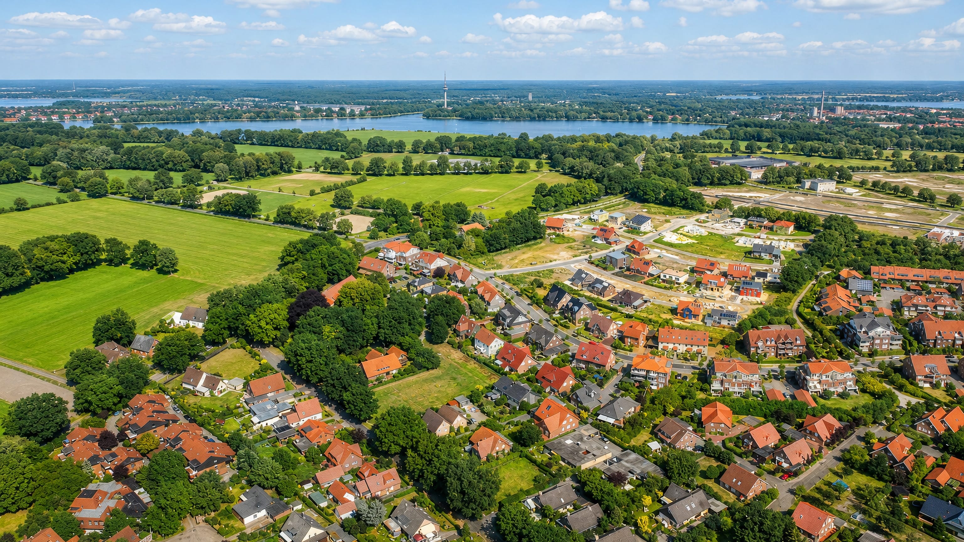 Aerial view of red-roofed houses, fields and a lake at Bloherfelde on the western edge of Oldenburg.