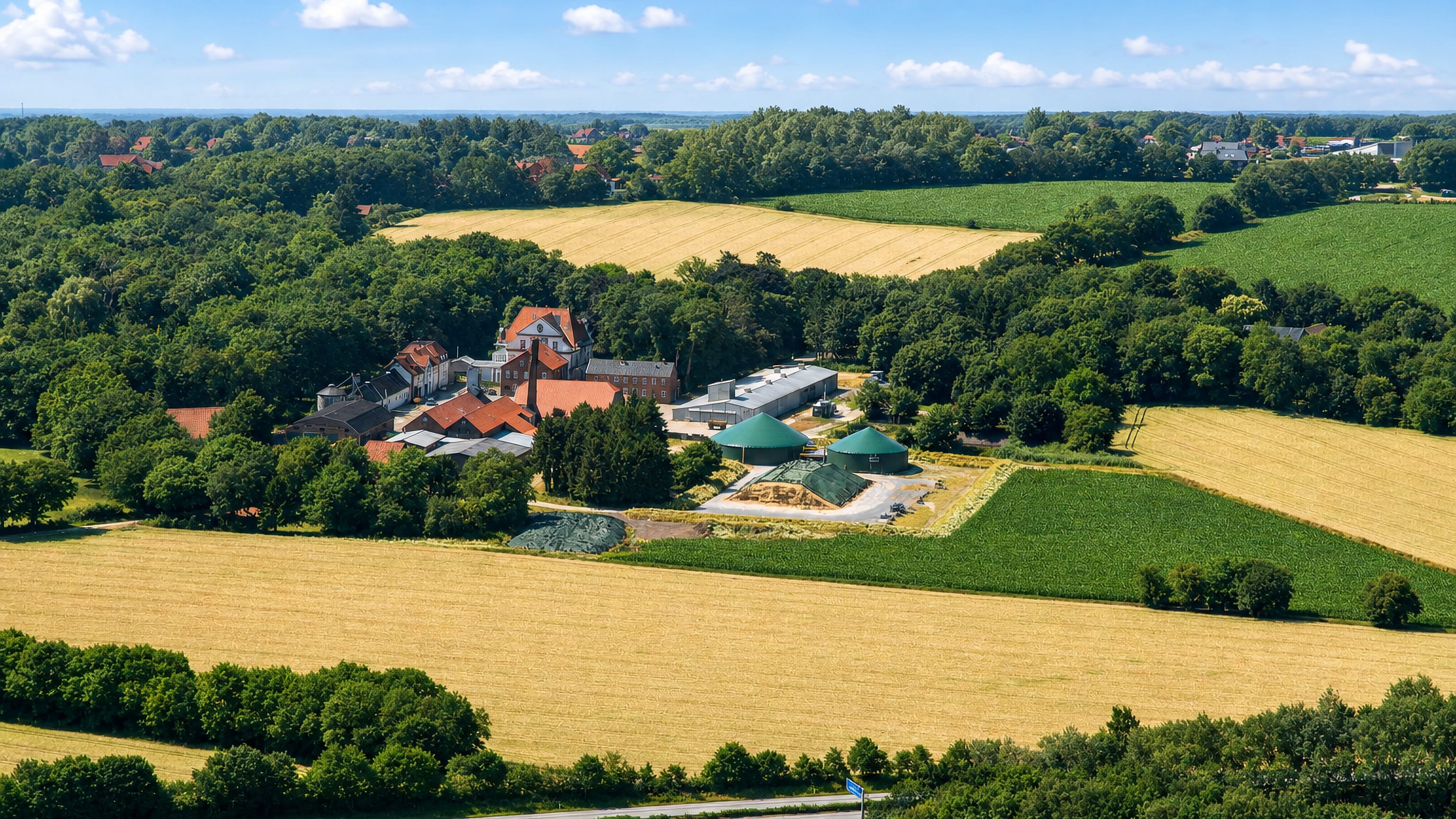 Farm estate with biogas tanks amid grain fields and hedgerows at Etzhorn on the northern edge of Oldenburg.