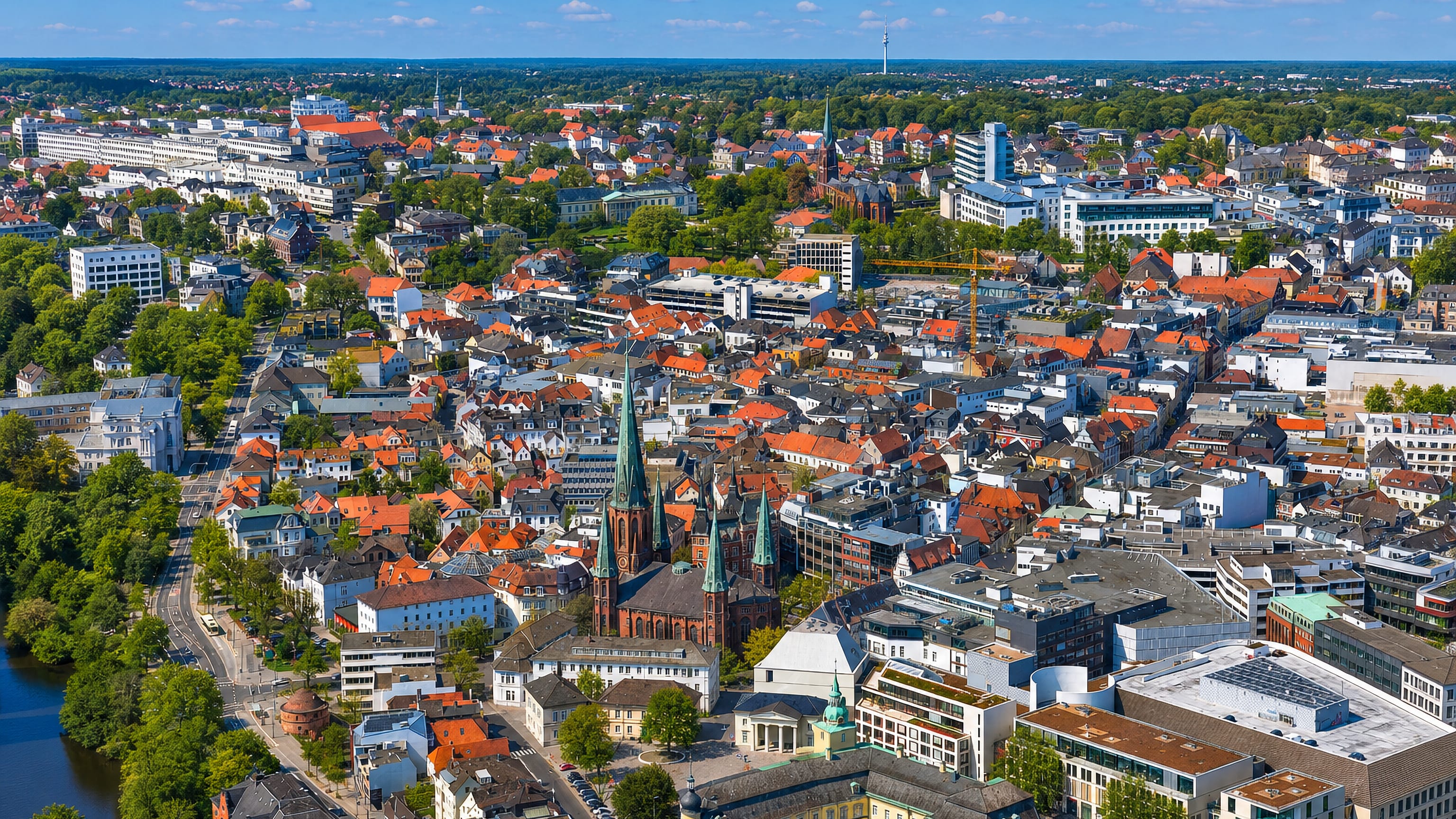 Aerial view over Oldenburg's red-roofed old town, its brick church spires and the yellow ducal palace.