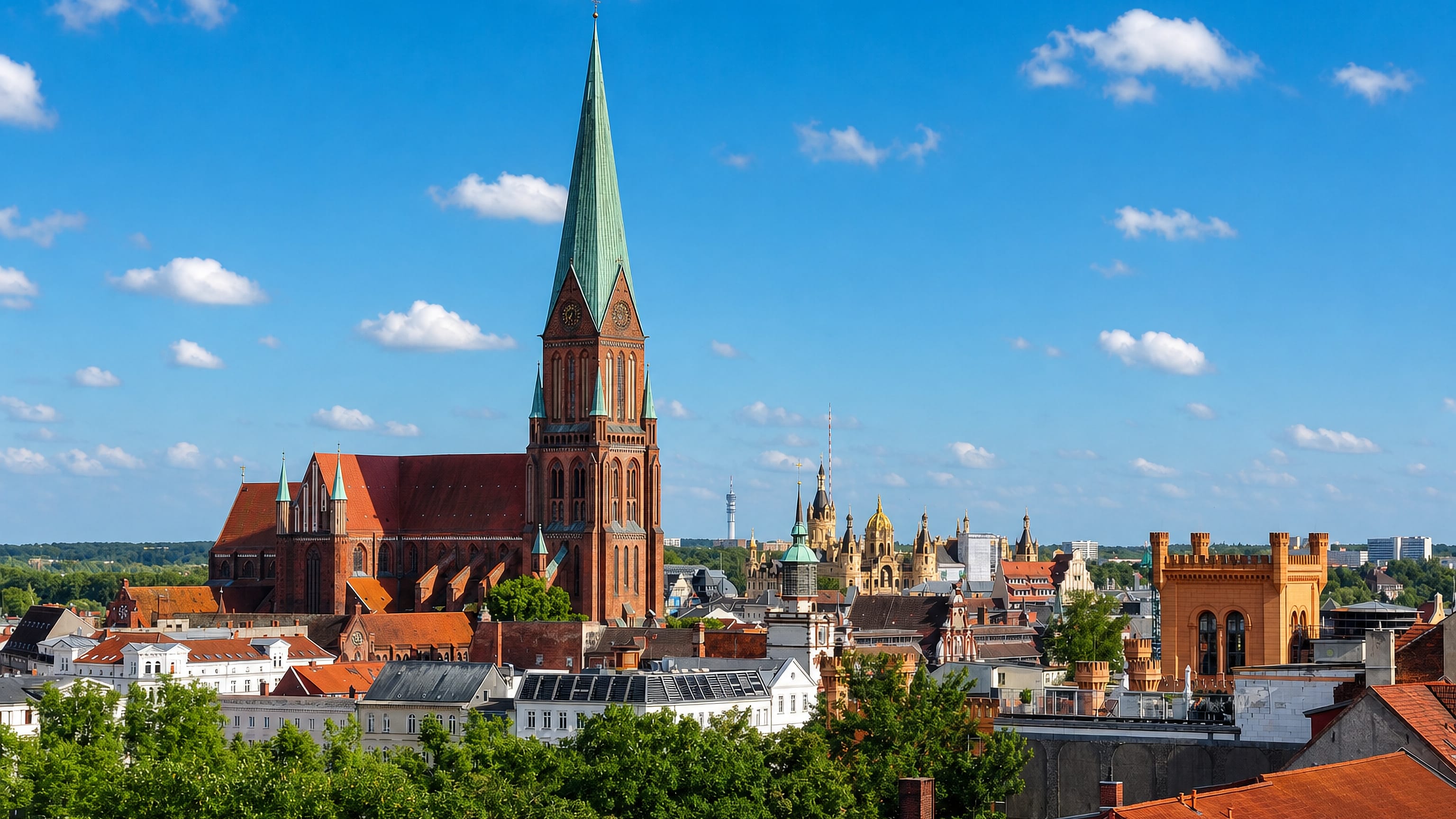 Schwerin's red-brick cathedral spire rising over old-town rooftops with Schwerin Castle's golden dome beyond.