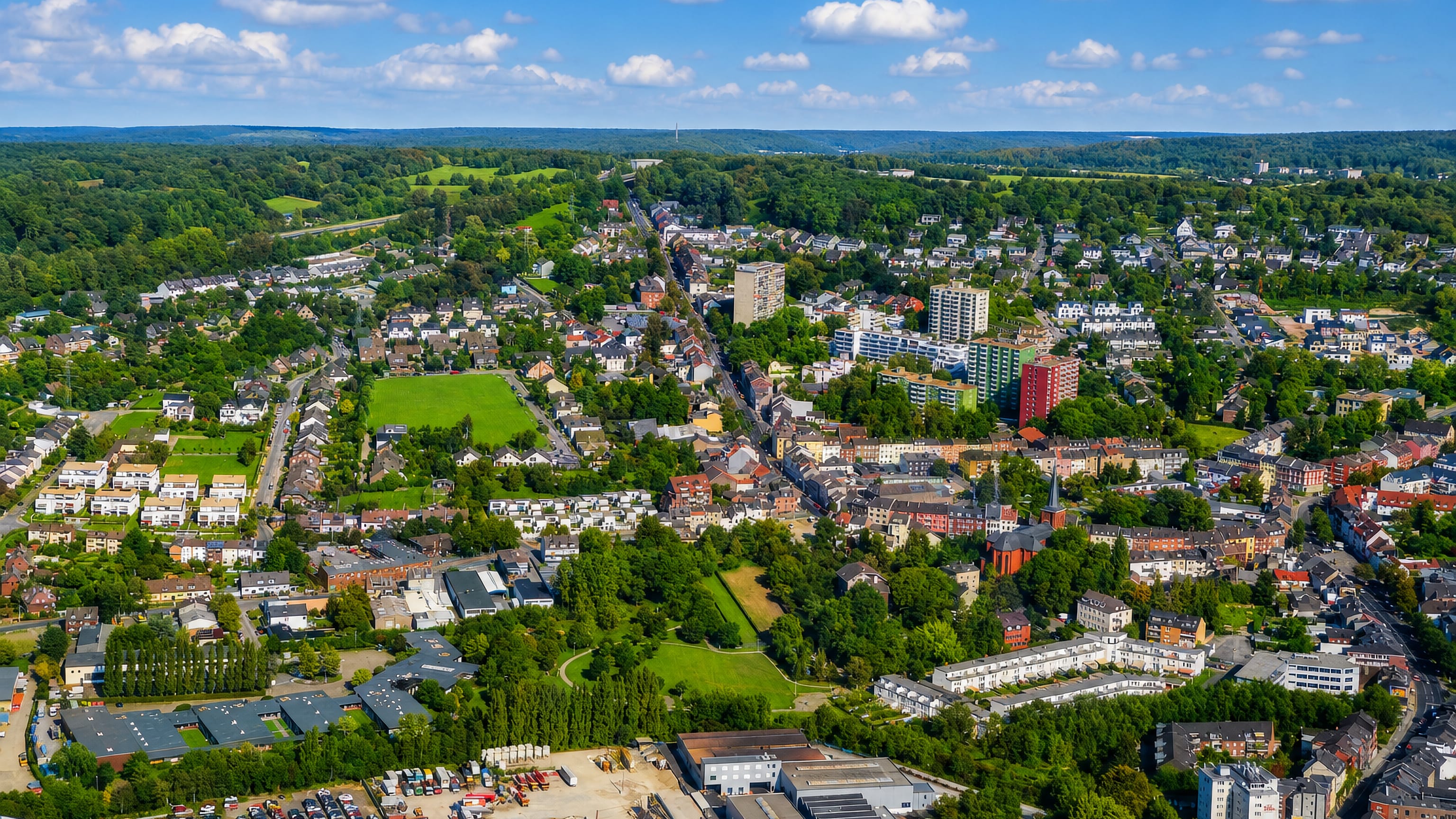 Aerial view over Haaren in Aachen, its church tower, tower blocks and industrial estate ringed by wooded hills