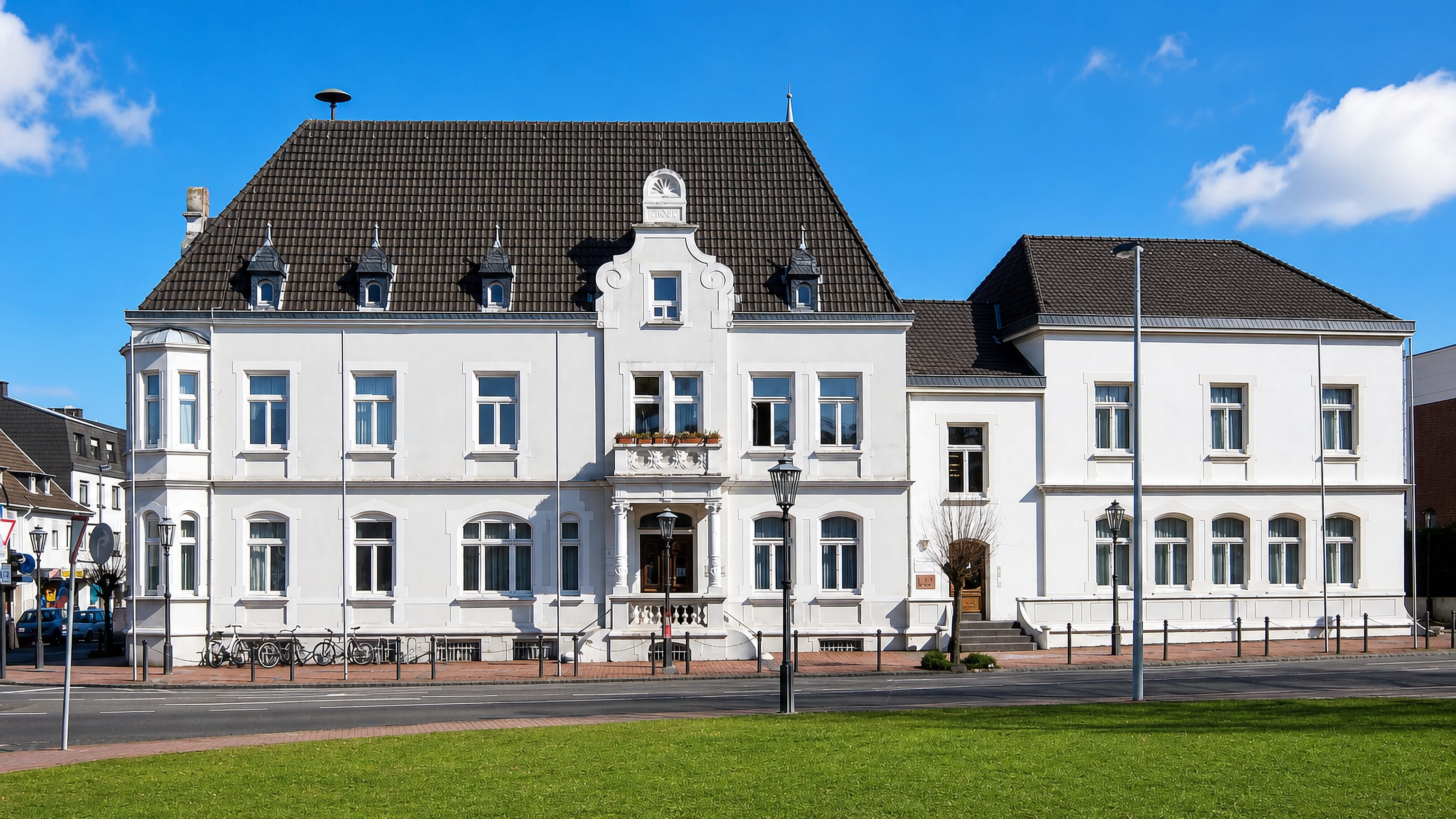 White gabled civic building with dormers, lawn and street lamps in Bonn Hardtberg.