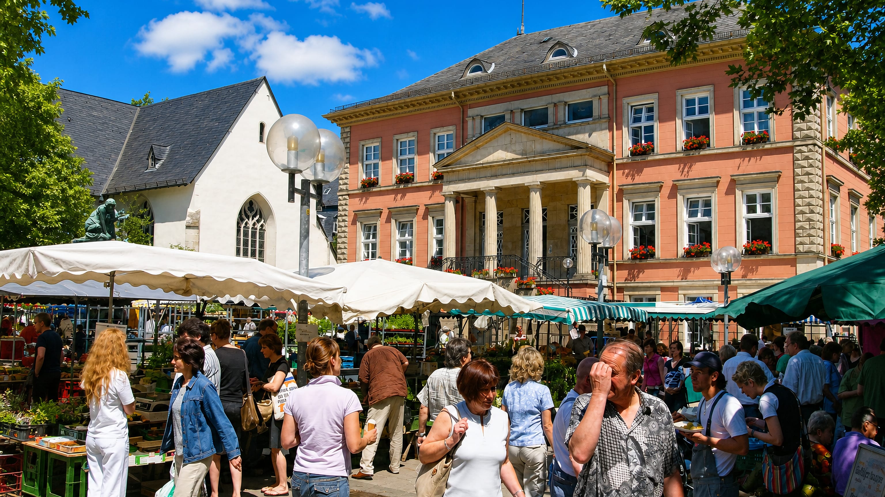 Market stalls filling Detmold's Marktplatz in front of the pink classicist town hall and its columned portico