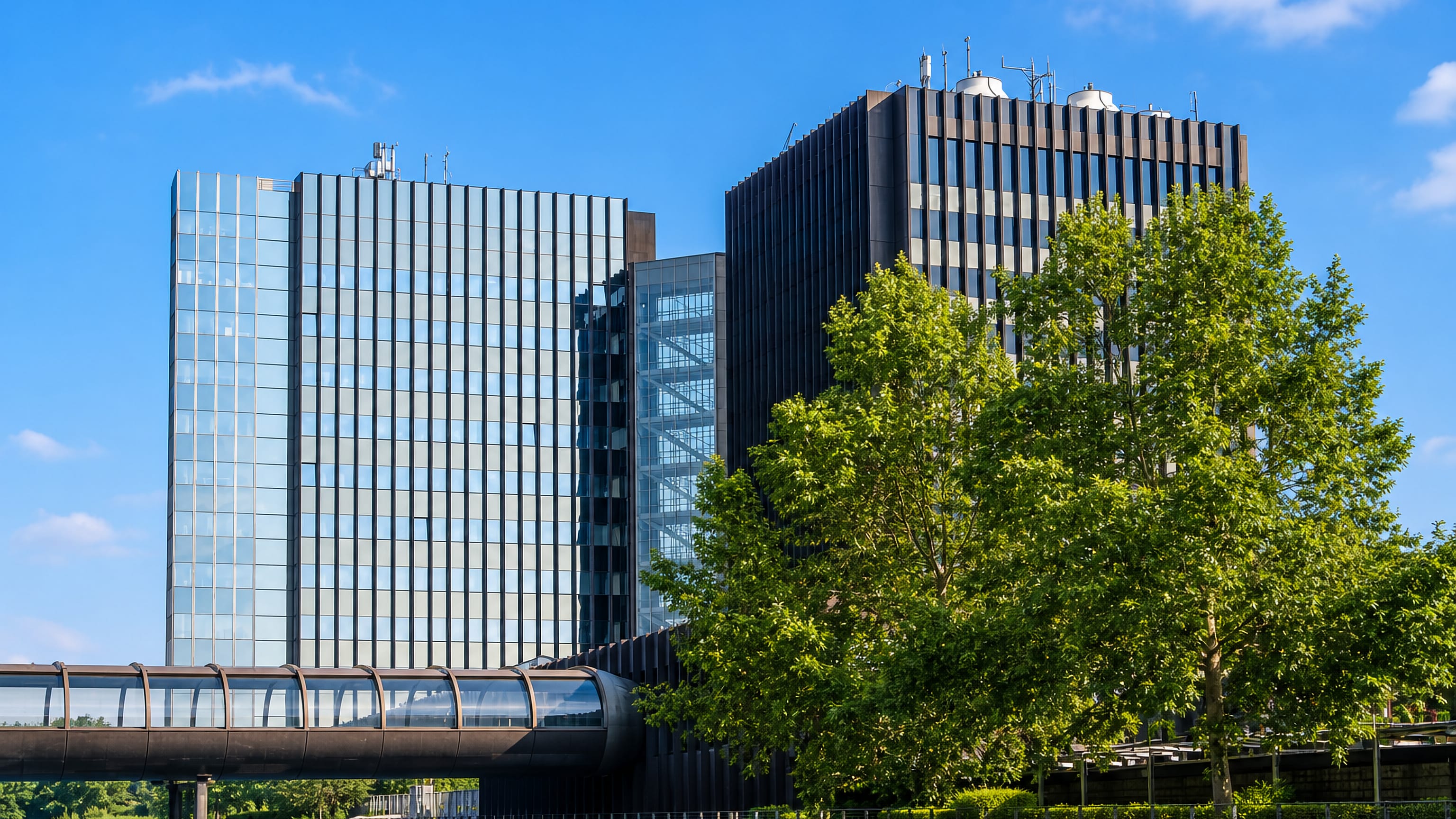 Dark glass office towers and an elevated transit tube beside the water in Stockum, Düsseldorf.