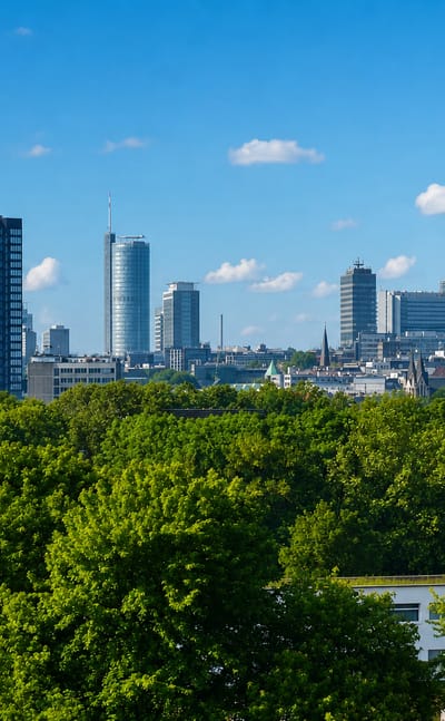 Essen's downtown skyline of modern office towers rising above a green tree line