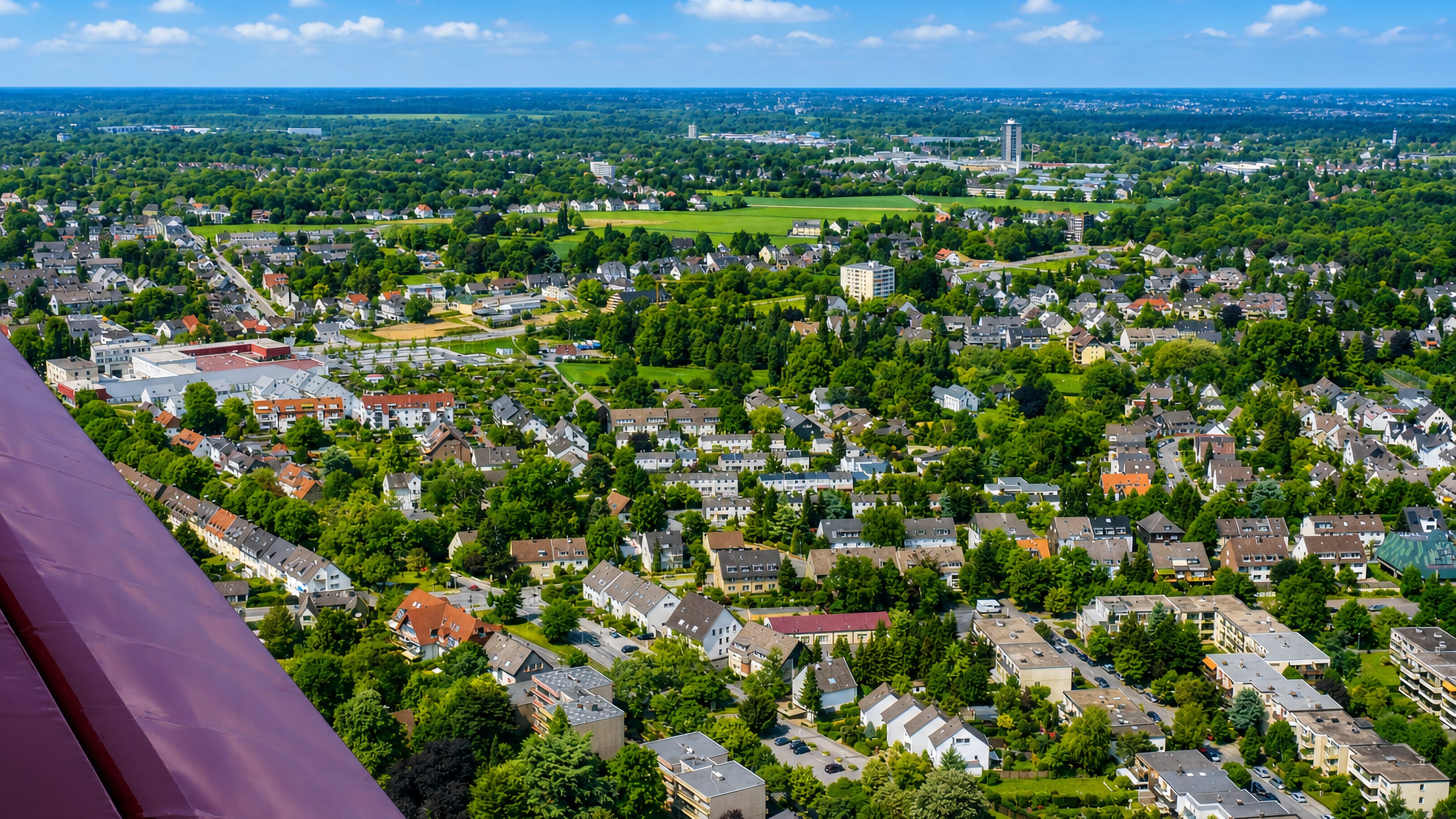 Aerial view over Haarzopf in Essen, its suburban houses and gardens spread out toward the airfield beyond.