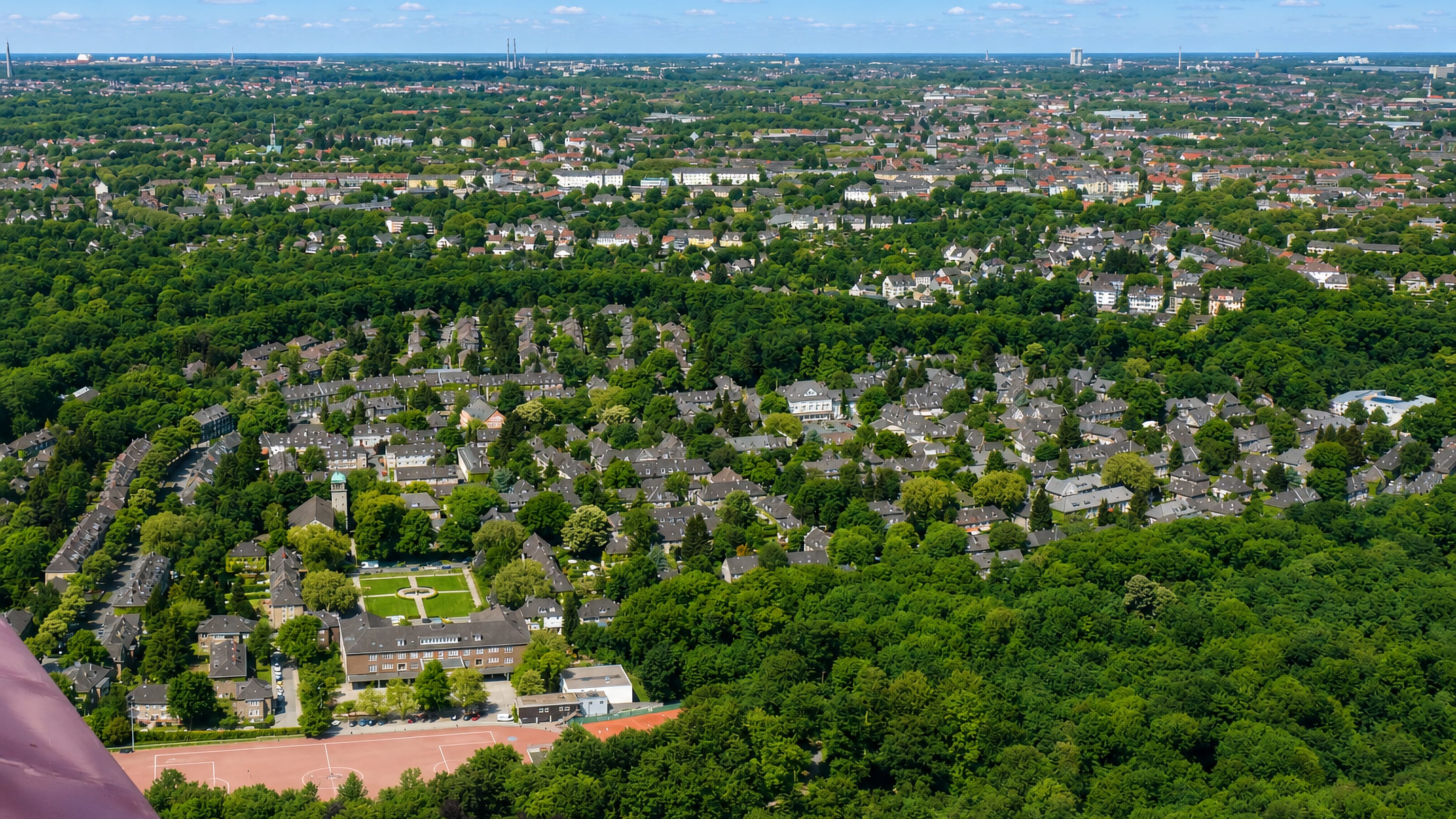 Aerial view over Margarethenhöhe's slate-roofed garden-city houses and wooded parkland in Essen.