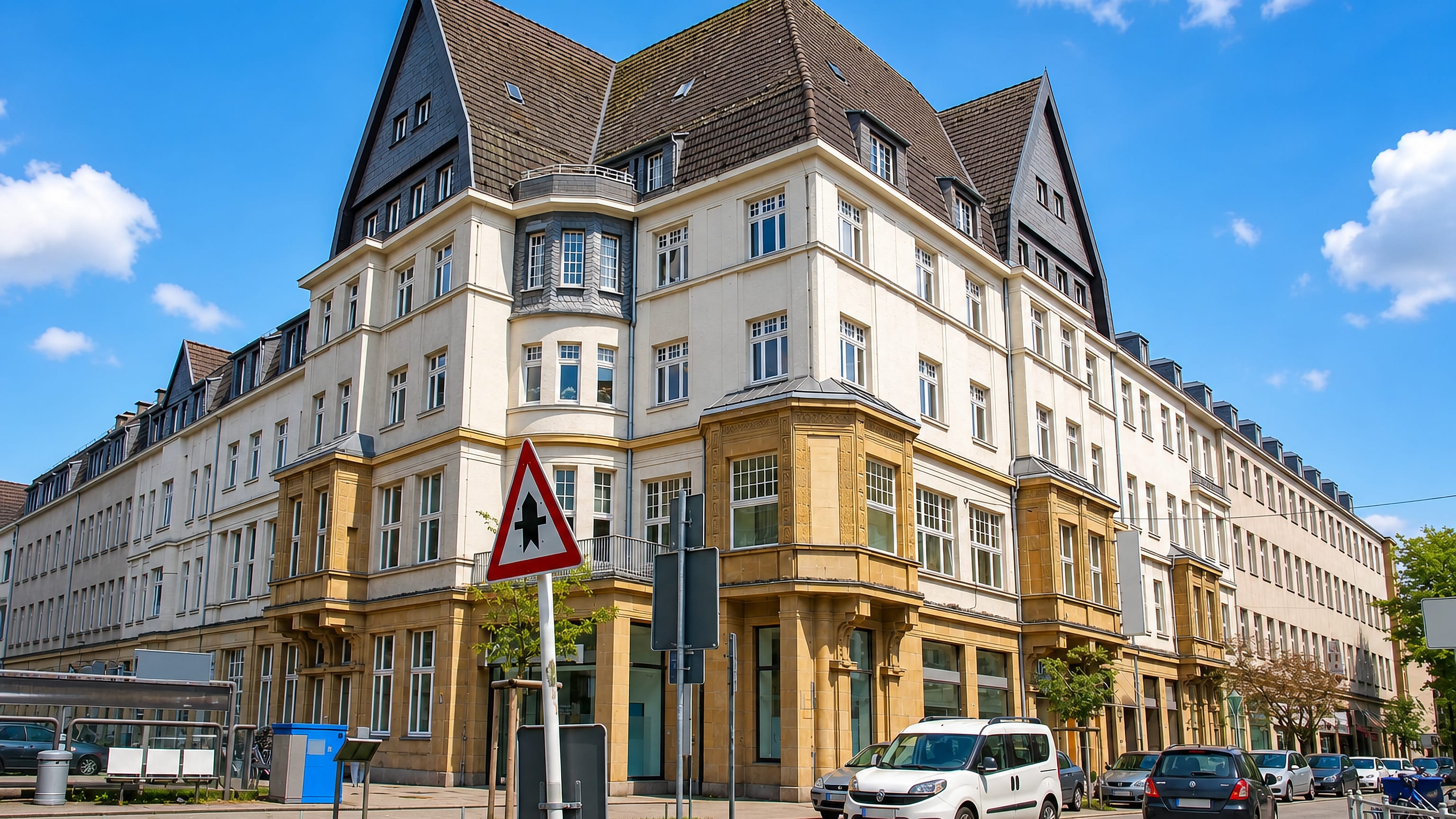 Gruenderzeit corner building with gabled roof and street-level shops on a sunny street in Ruettenscheid, Essen.