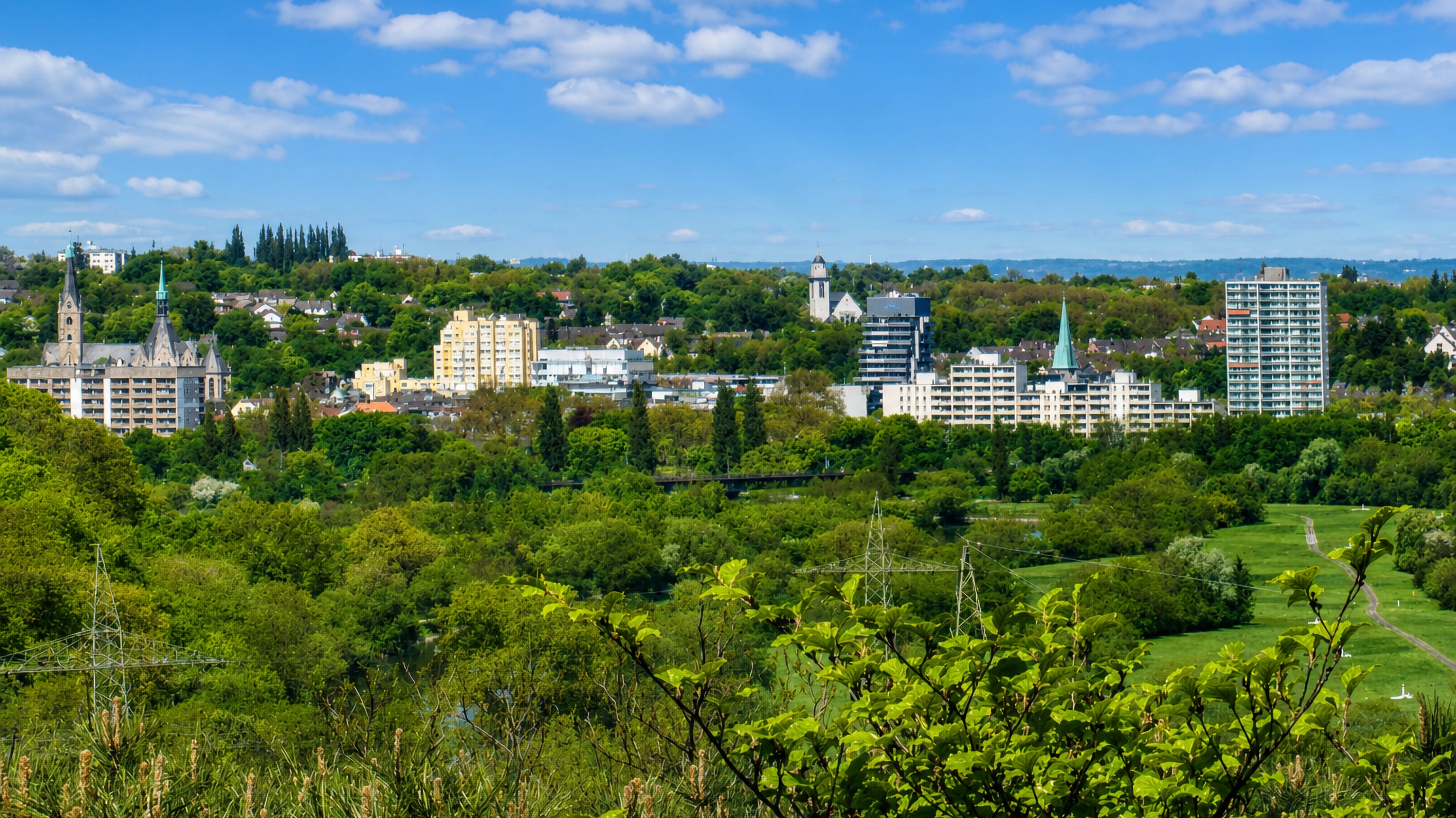 Steele in Essen seen across the green Ruhr valley, its church spires and apartment towers on the far bank