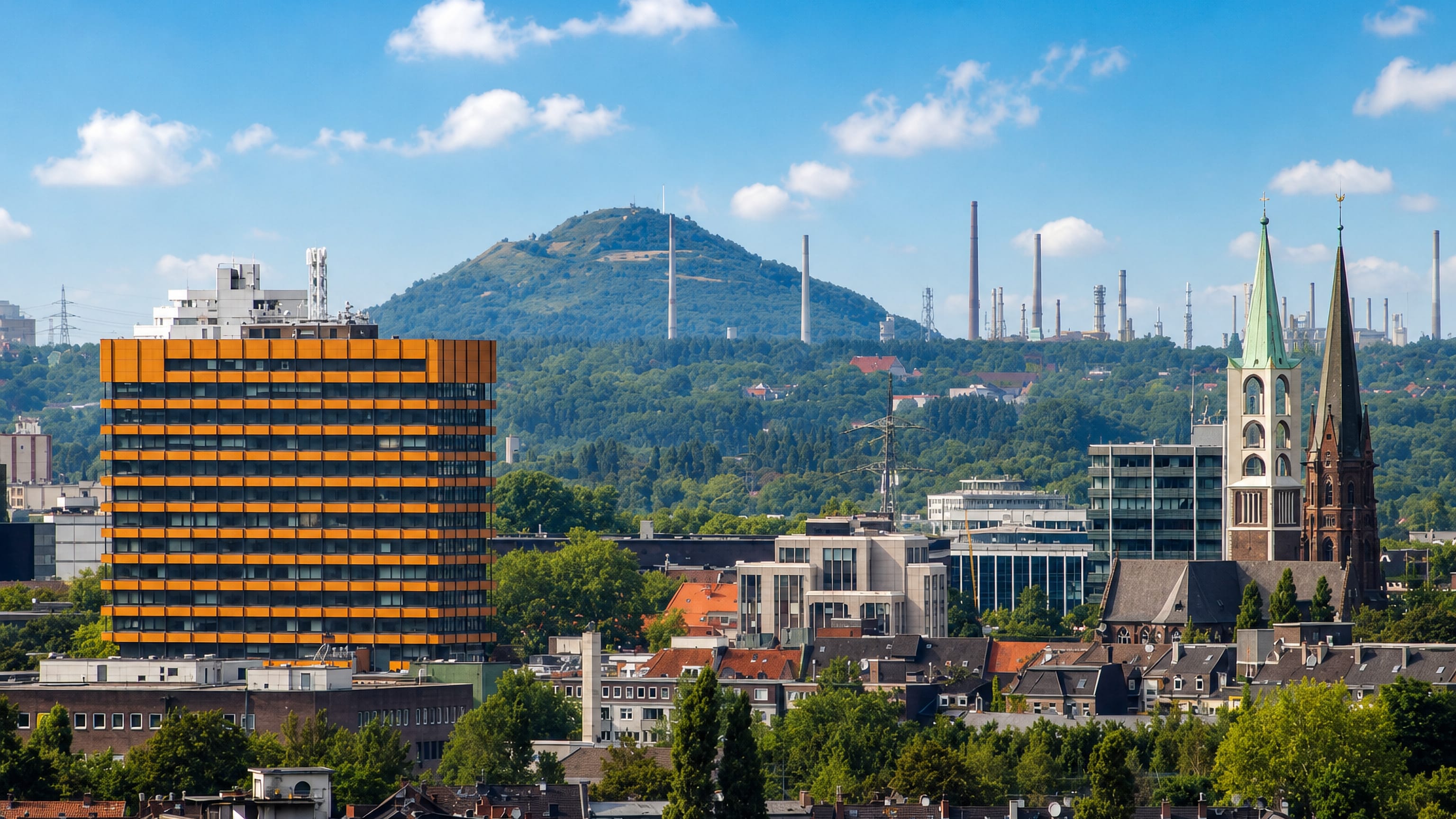 Gelsenkirchen skyline with a tall orange-clad office block, church spires and refinery chimneys on a wooded ridge.
