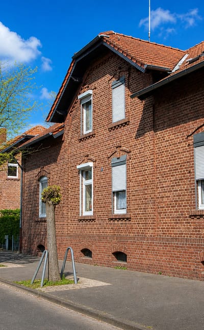 Red-brick miners' terraces with pollarded trees lining a quiet residential street in Rentfort.