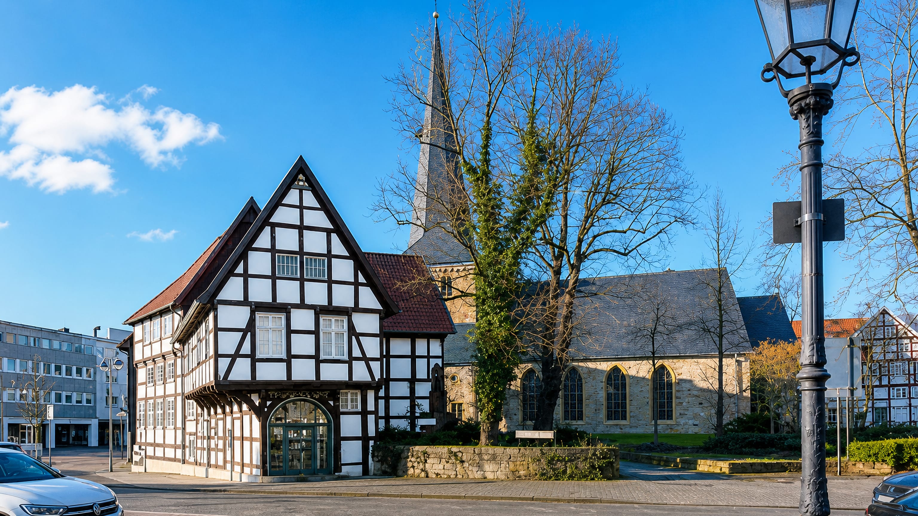 Half-timbered house and stone church on a sunny street corner in central Gütersloh, Germany