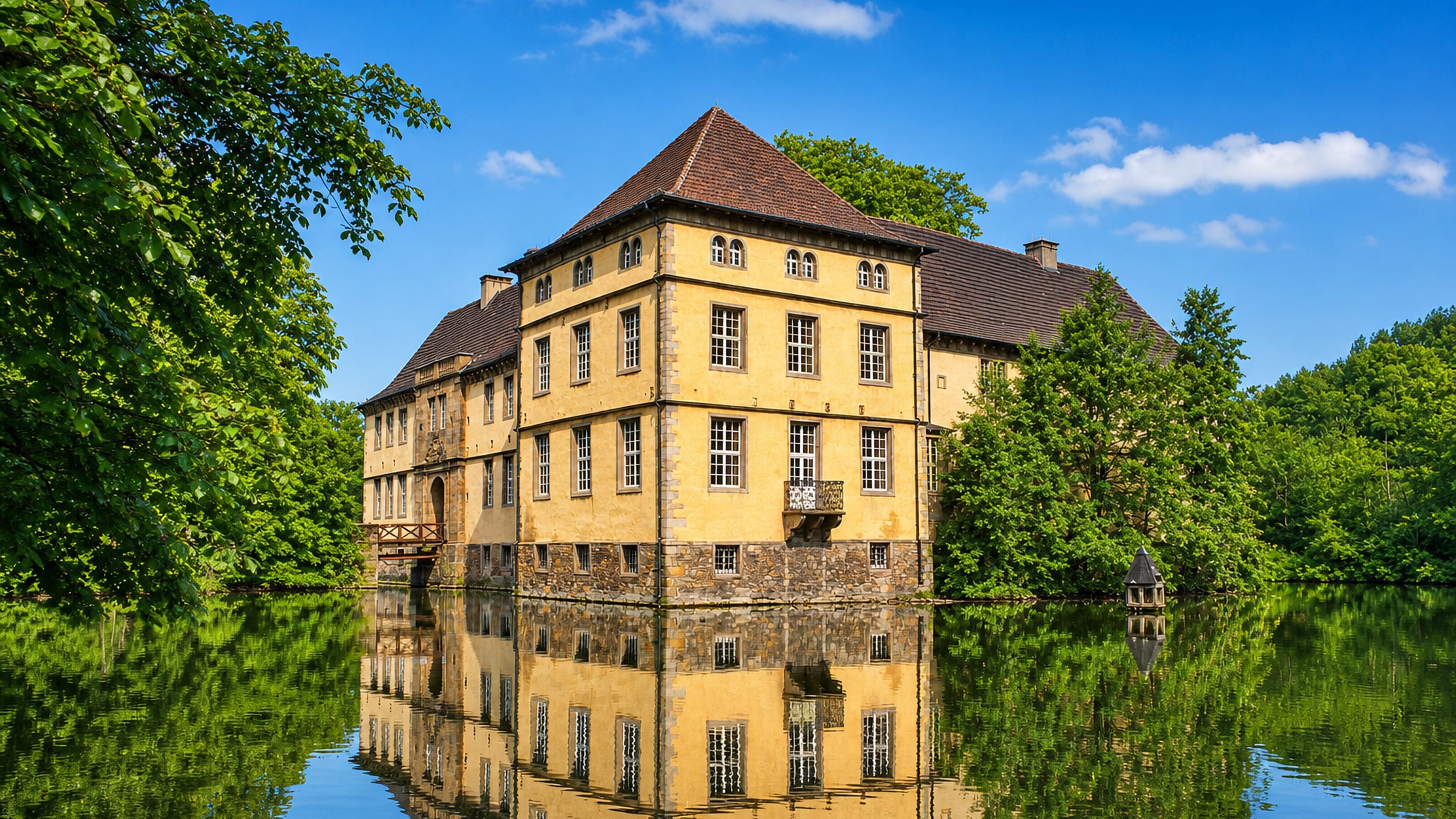 Moated Renaissance manor house at Baukau in Herne, reflected in its still green moat