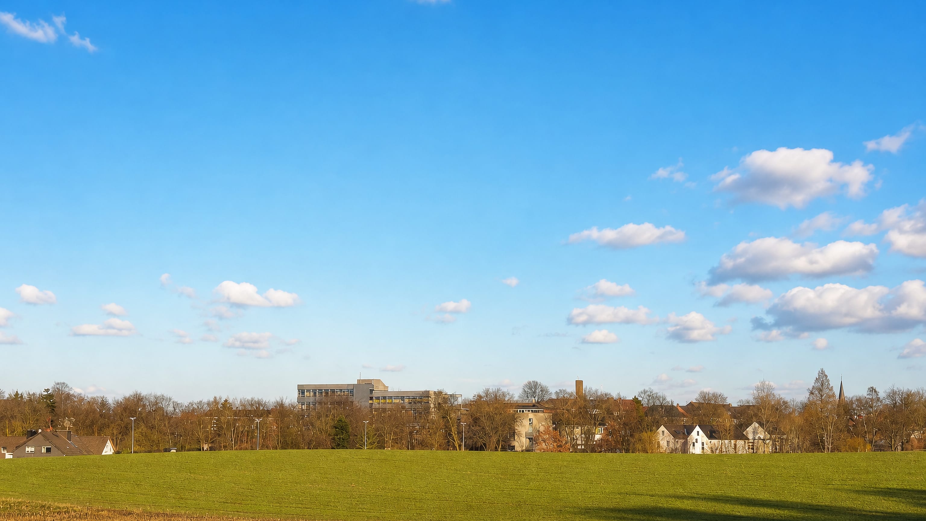 Distant rooftops and a church spire of Sodingen, Herne, seen across open farmland.