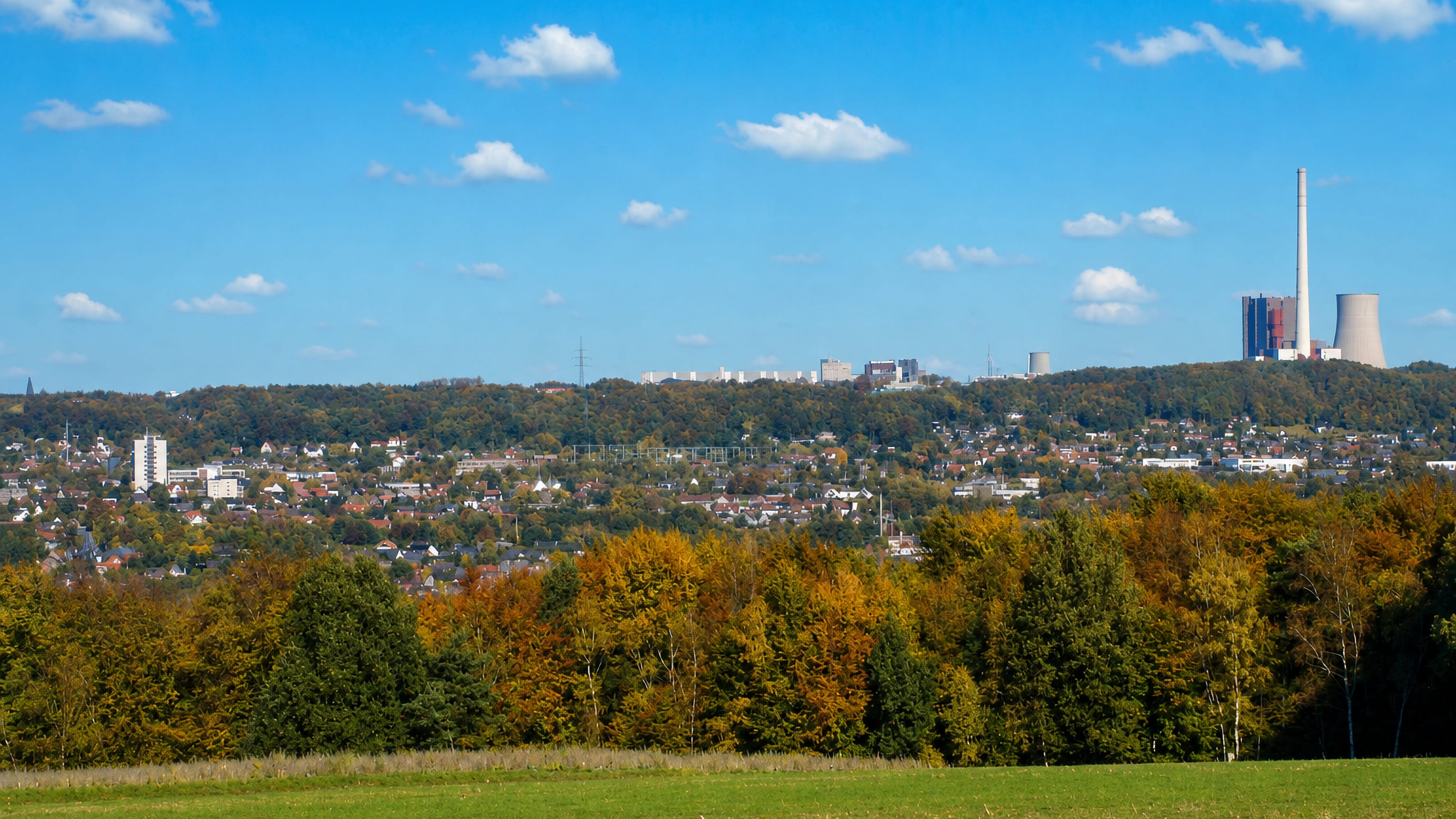 Autumn panorama across wooded ridges to Ibbenbüren, Germany, with its power station chimney and cooling tower.