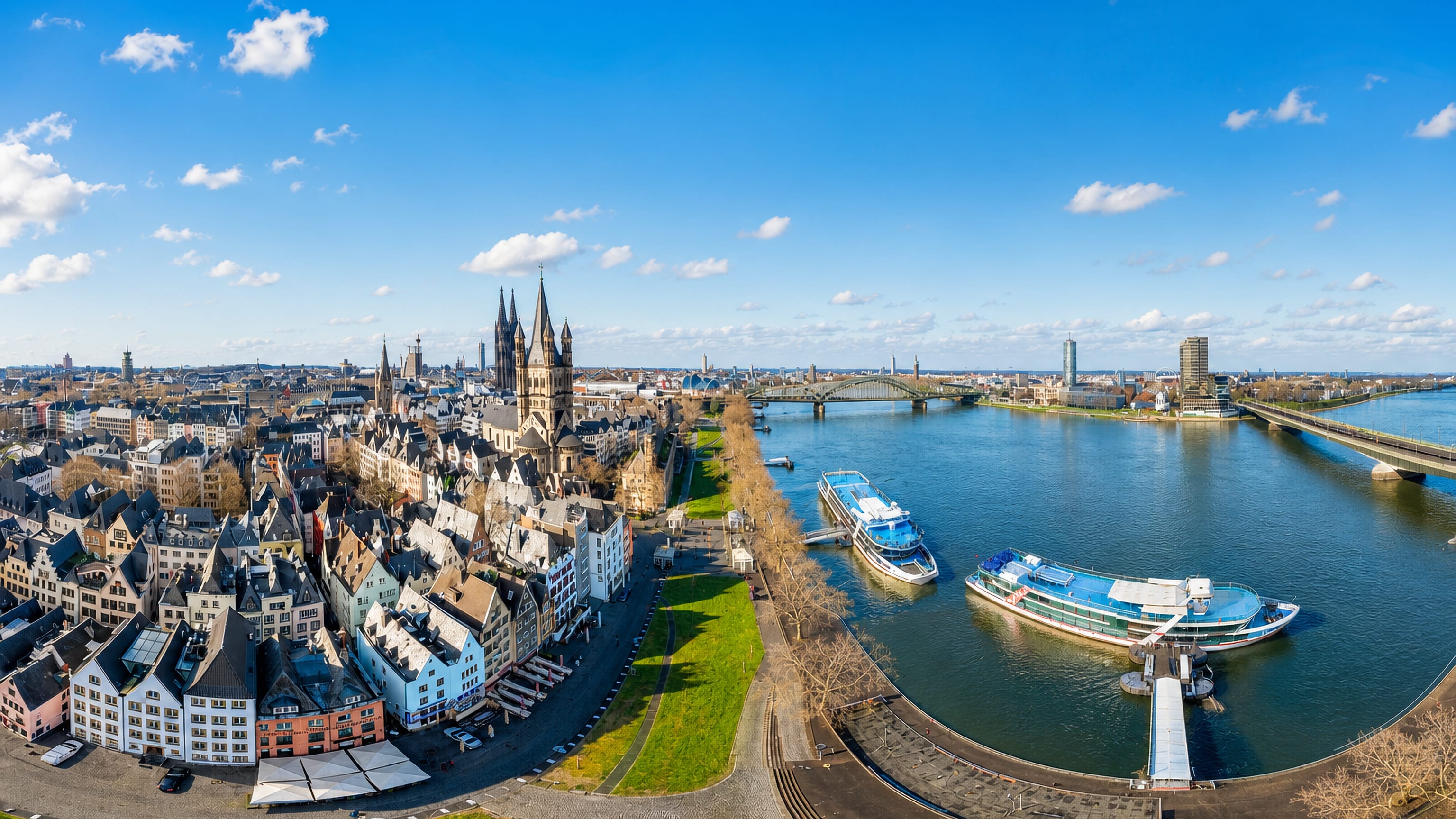 Aerial view of Cologne's Altstadt-Nord, gabled old-town houses and Gross St. Martin beside the Rhine and its riverboats.