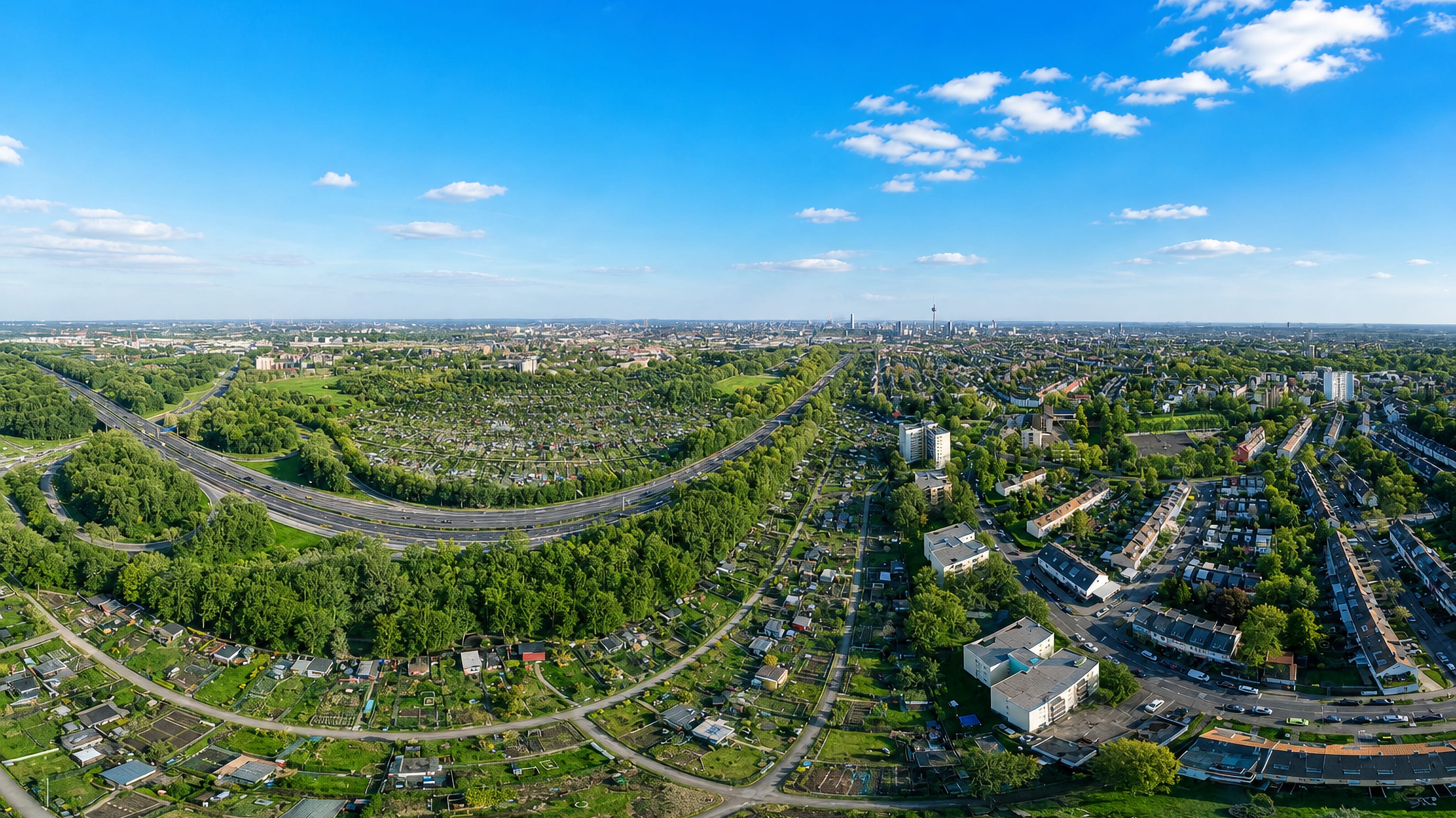 Aerial over Bilderstöckchen in Cologne, with allotment gardens, the ring road and the distant city skyline.