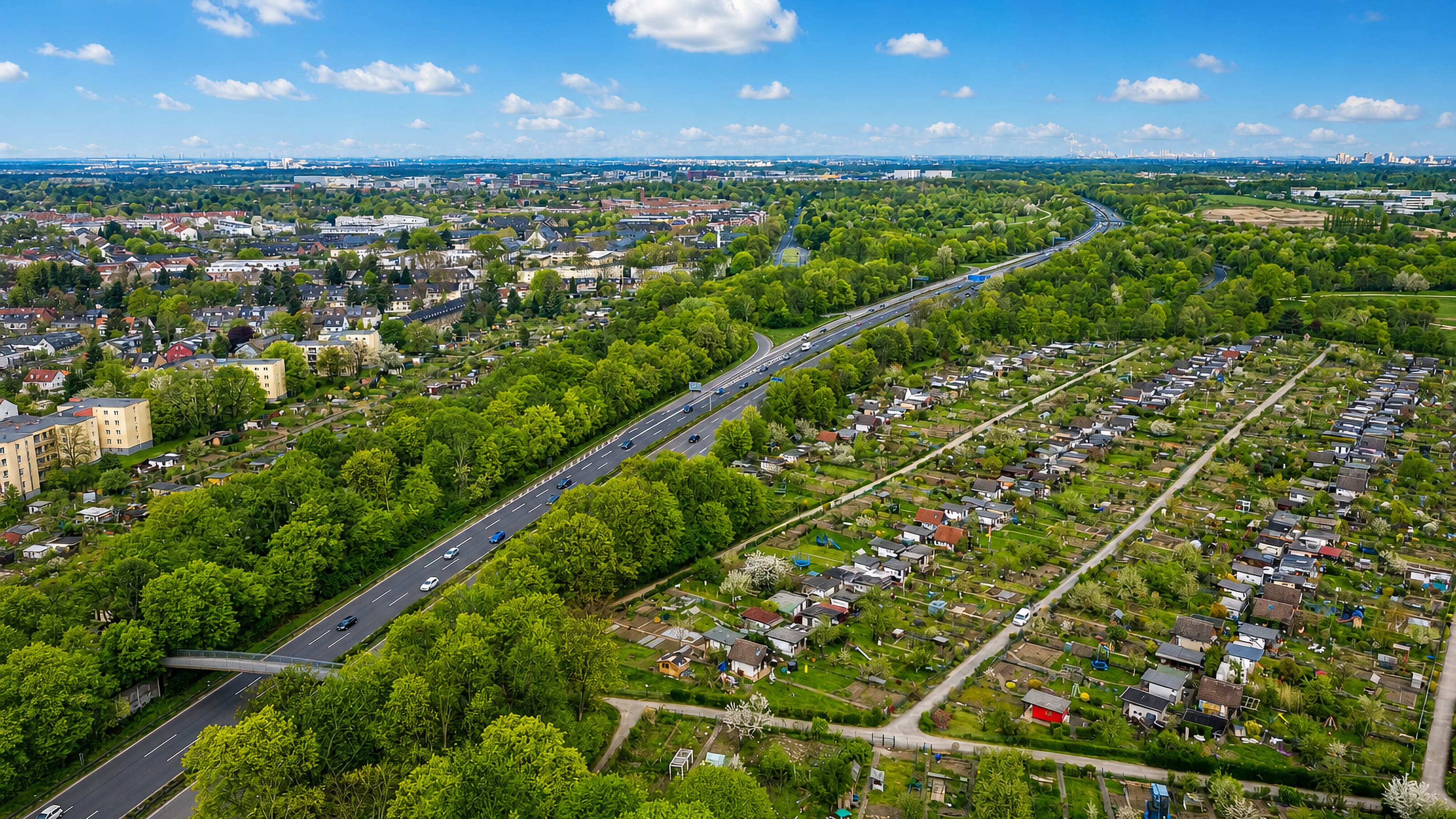 Aerial view over Ossendorf, Cologne, showing allotment gardens, wooded streets and a motorway cutting through.