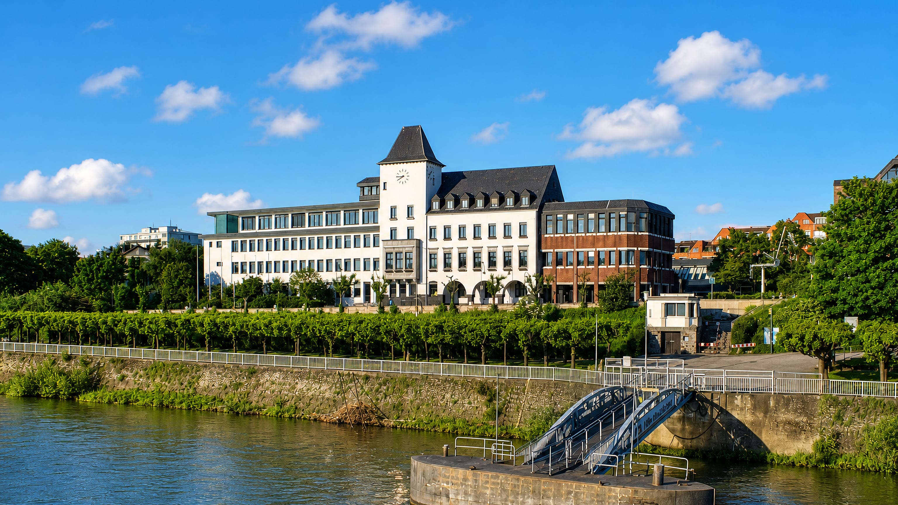 White clock-tower building above the Rhine embankment at Porz am Rhein, Cologne, on a sunny day.