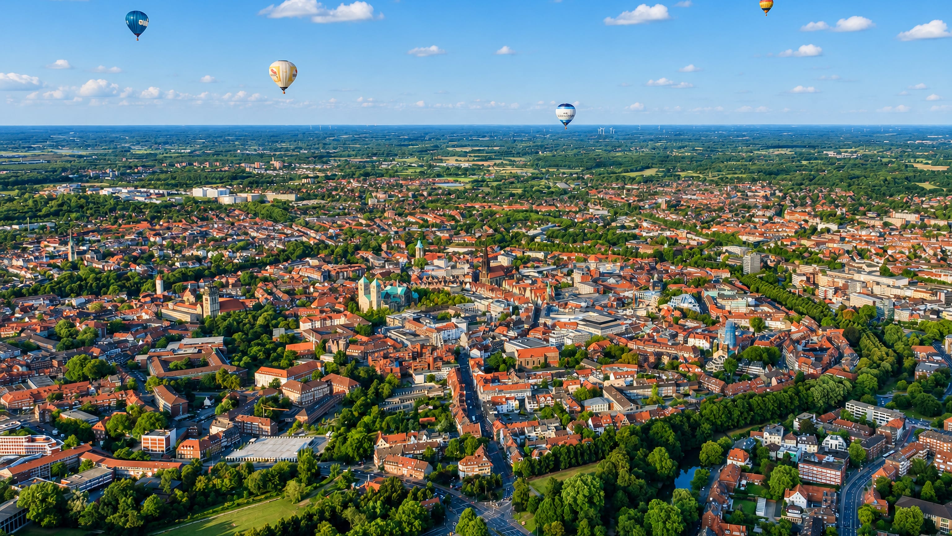 Aerial view of Münster's old town, St Paulus Cathedral and the green Promenade ring, balloons overhead