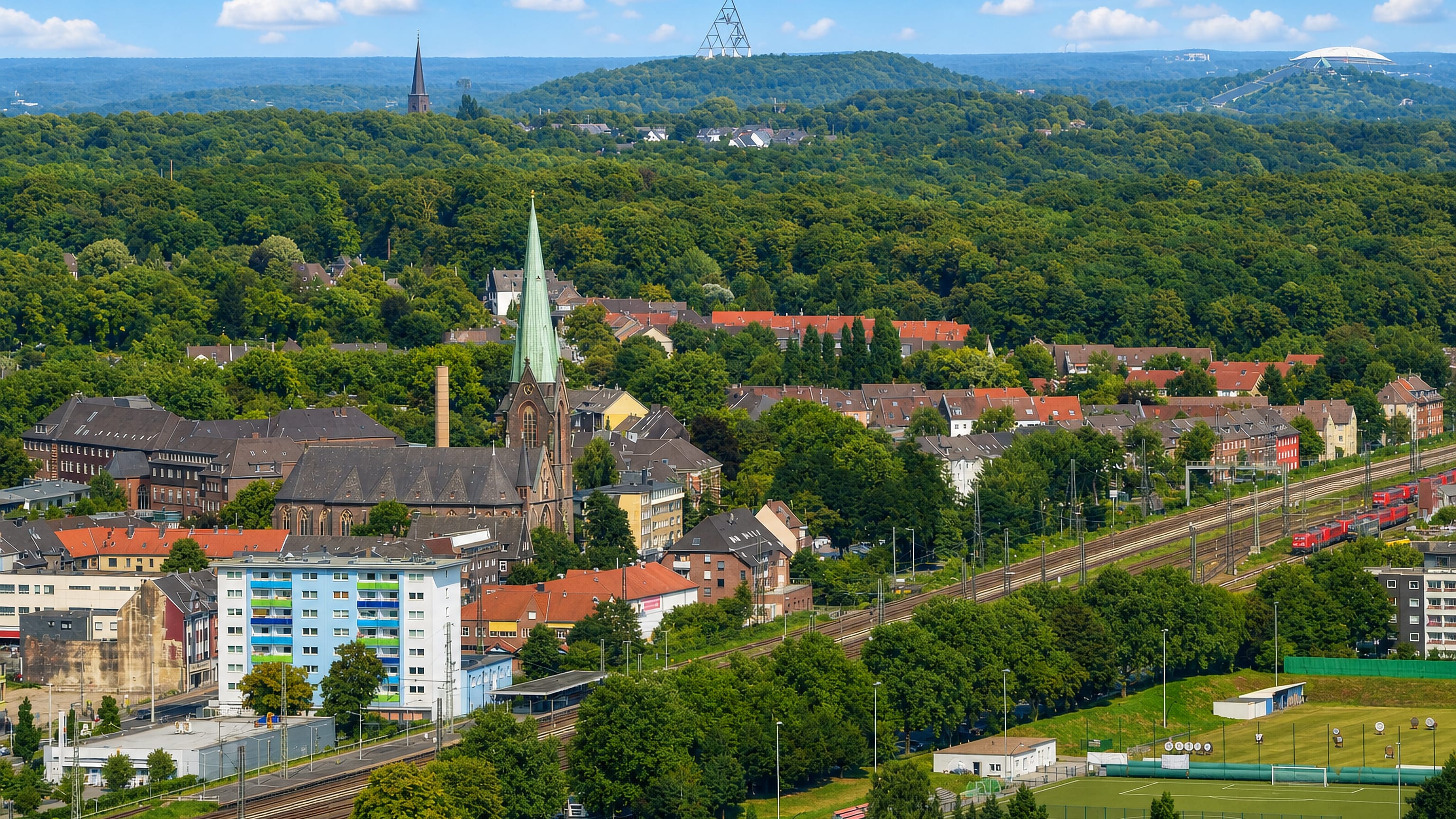 Osterfeld's brick church spire, rail yards and wooded hills, with Bottrop's Tetraeder on the horizon