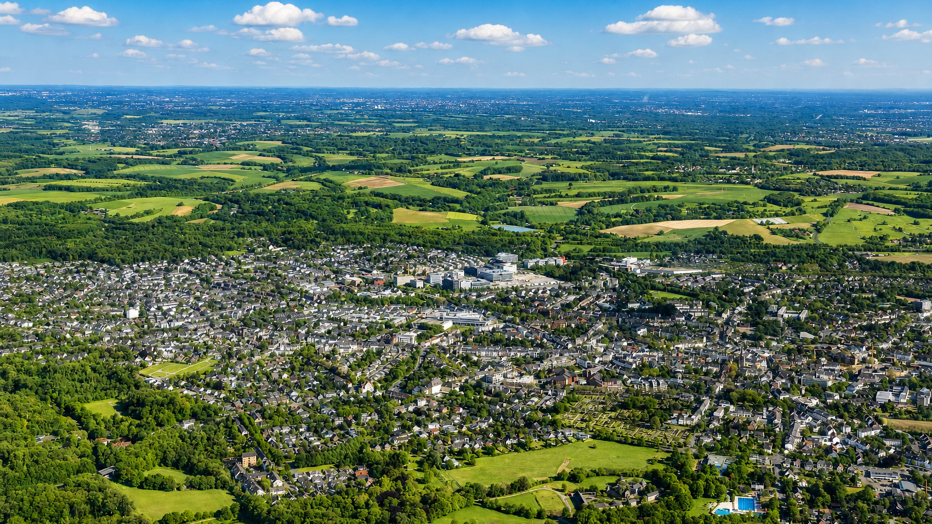 High aerial view of Ratingen, Germany, its rooftops and green belts spreading across the Rhineland plain.