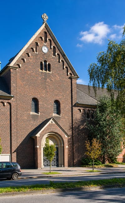 Red-brick church with a green spire and adjoining brick buildings in Stuckenbusch, Recklinghausen.