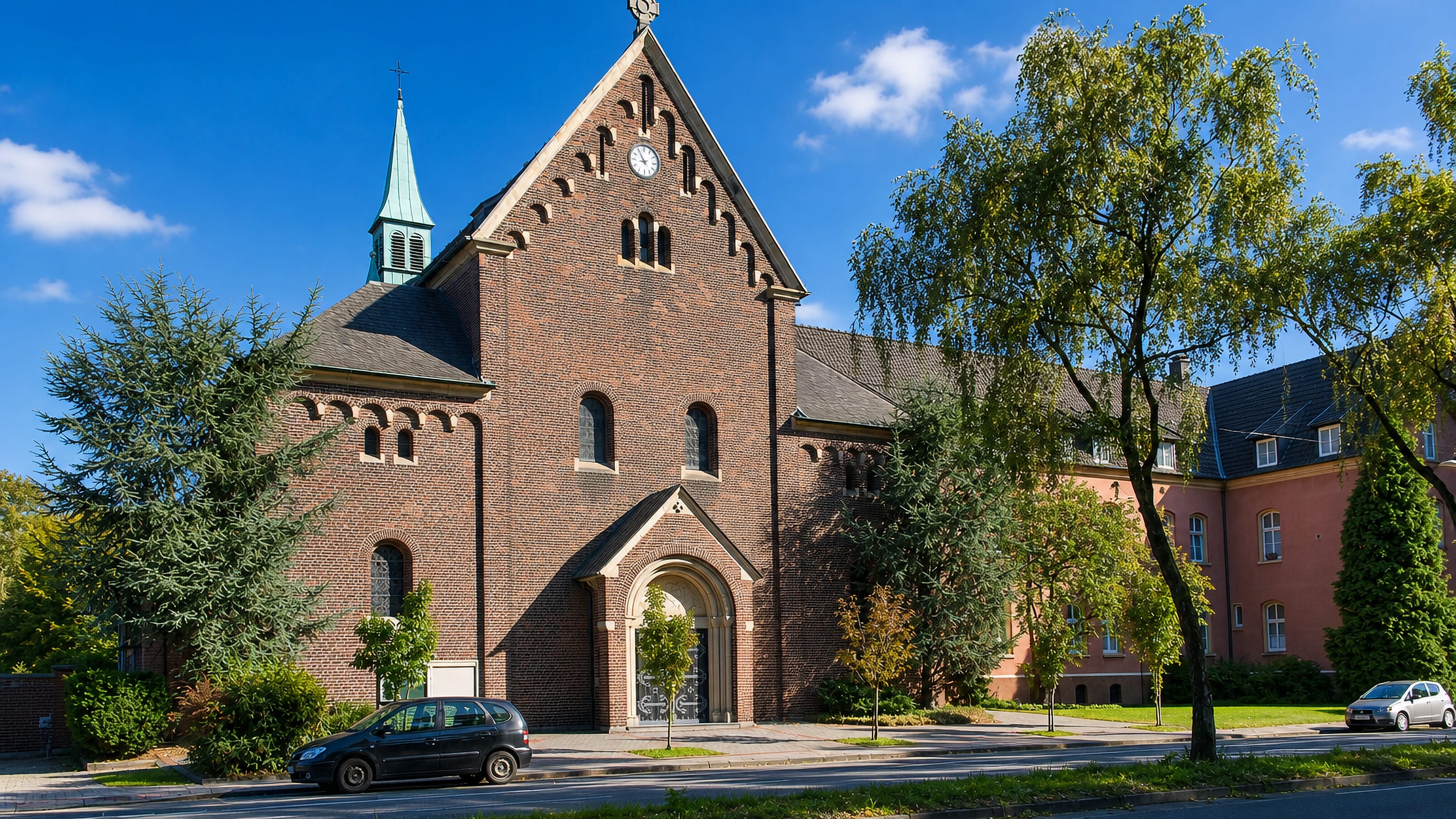 Red-brick church with a green spire and adjoining brick buildings in Stuckenbusch, Recklinghausen.