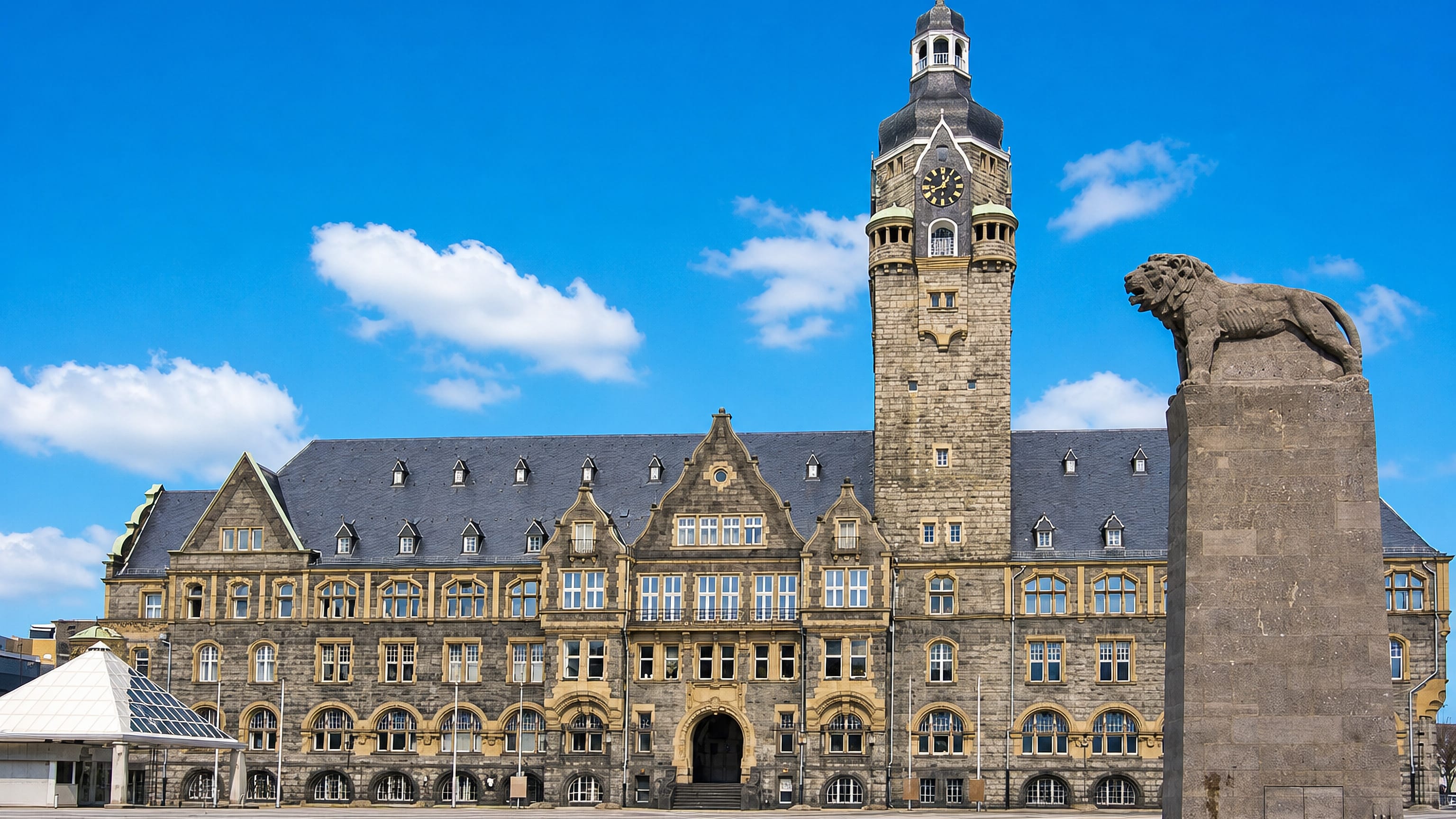 Remscheid's sandstone town hall and clock tower rising over the open square, with the lion monument alongside.