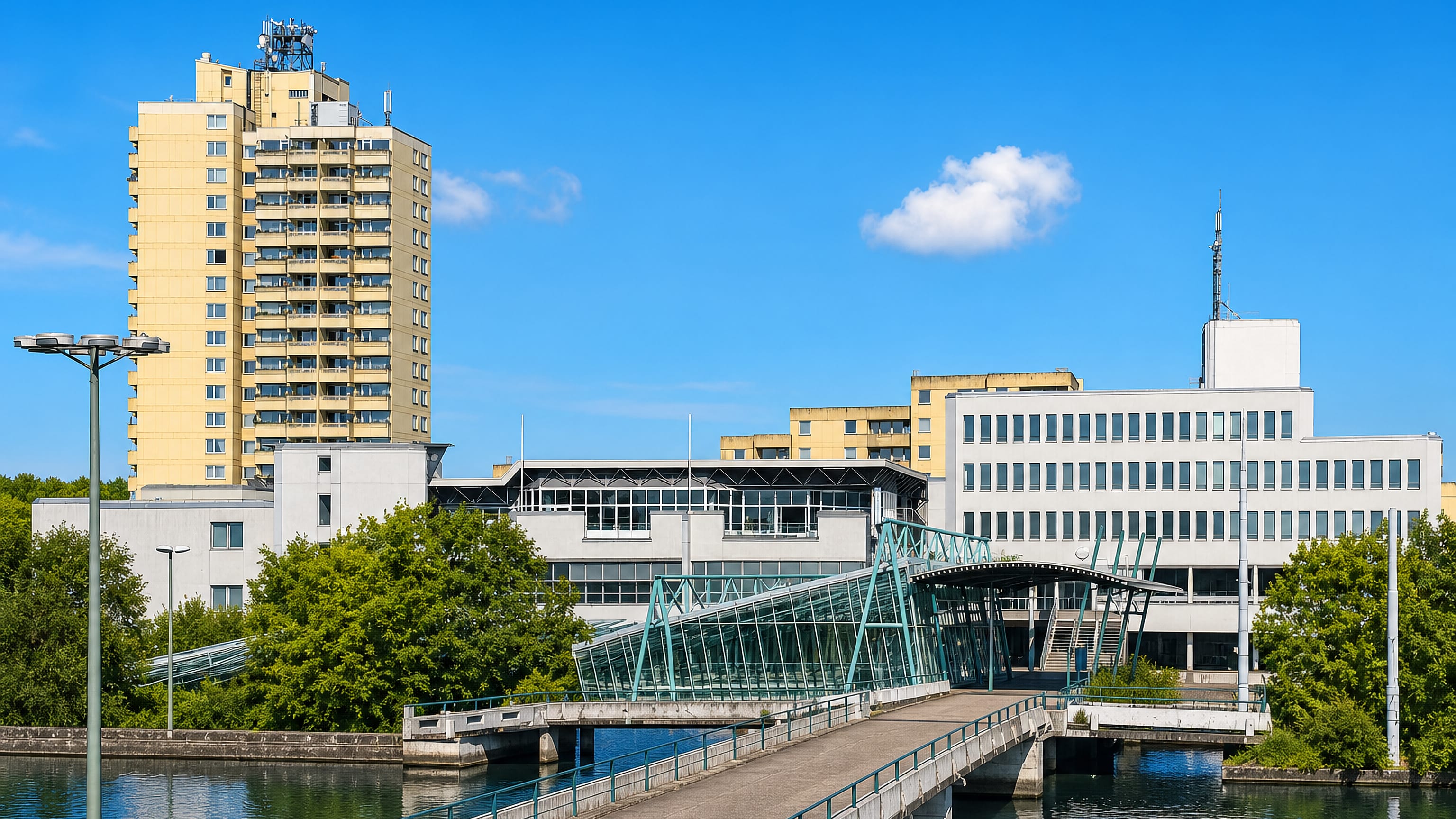 Modernist campus buildings, a high-rise and a glazed footbridge over water in Querenburg, Bochum.