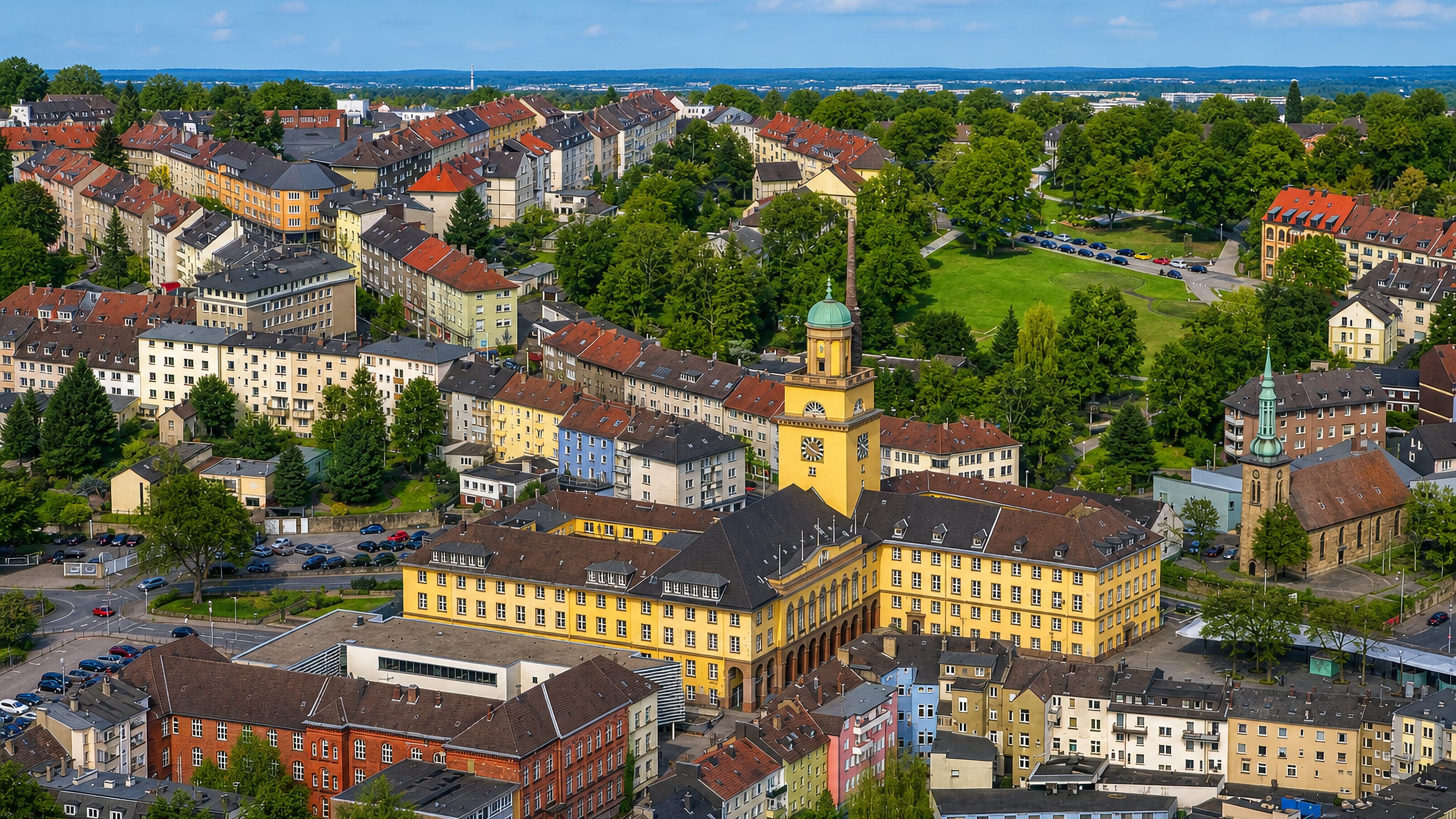 Aerial view of Witten in North Rhine-Westphalia, its yellow town hall and clock tower amid tiled rooftops.