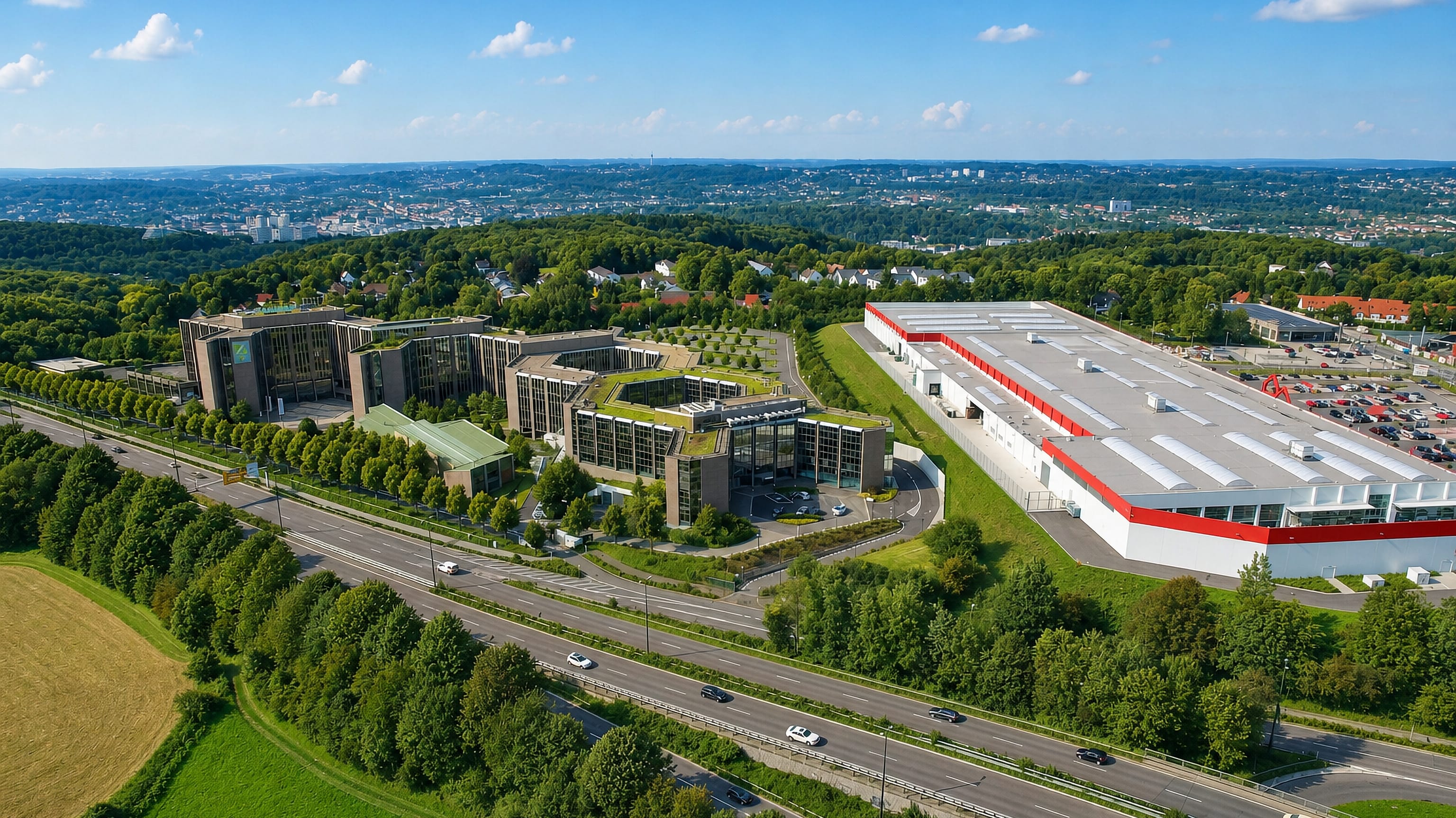 Aerial view over offices and a retail hall beside the motorway at Lichtenplatz, Wuppertal, hills beyond.