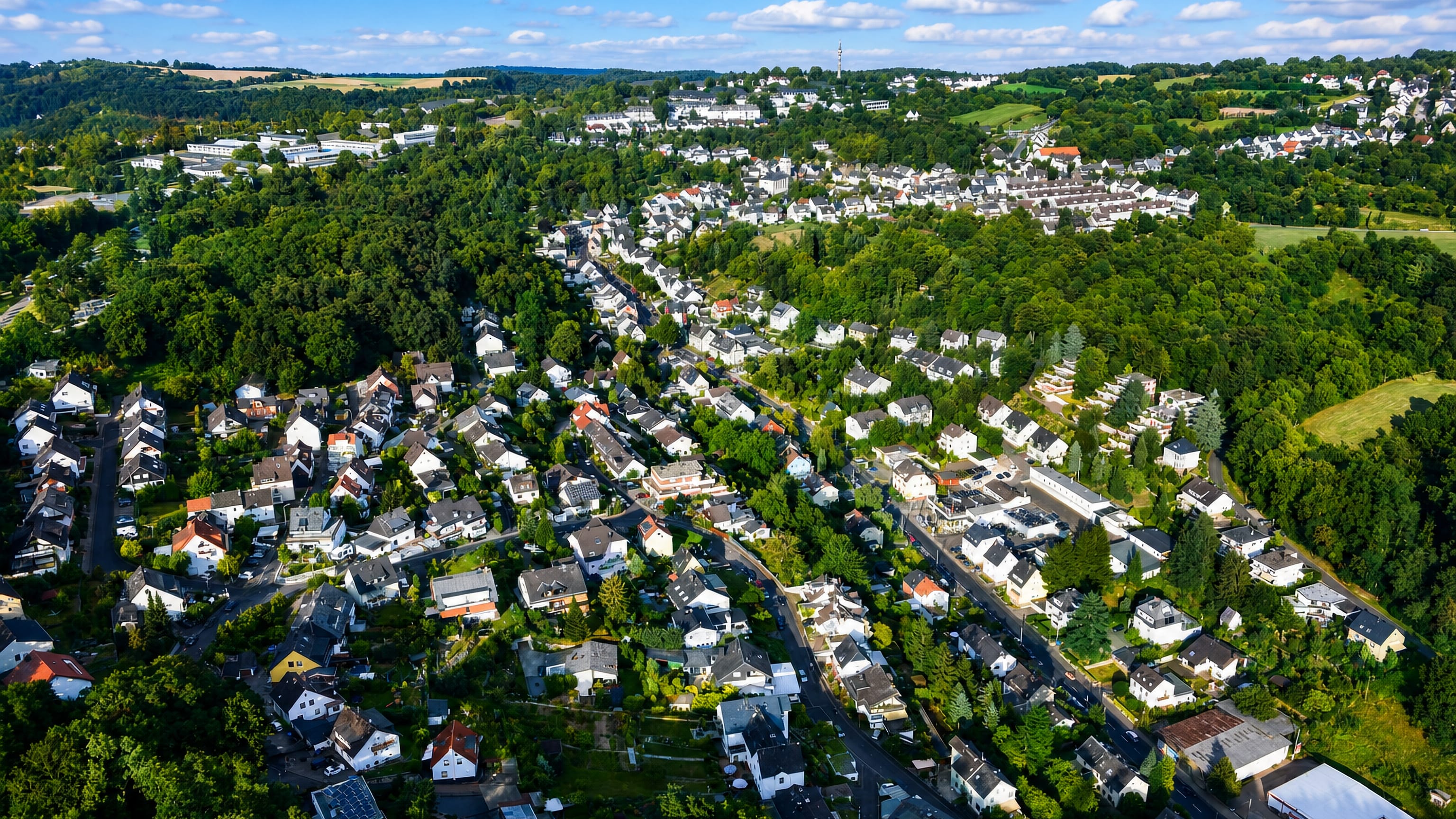 Aerial of Niederberg, Koblenz, with houses spread across wooded hillsides above the city.