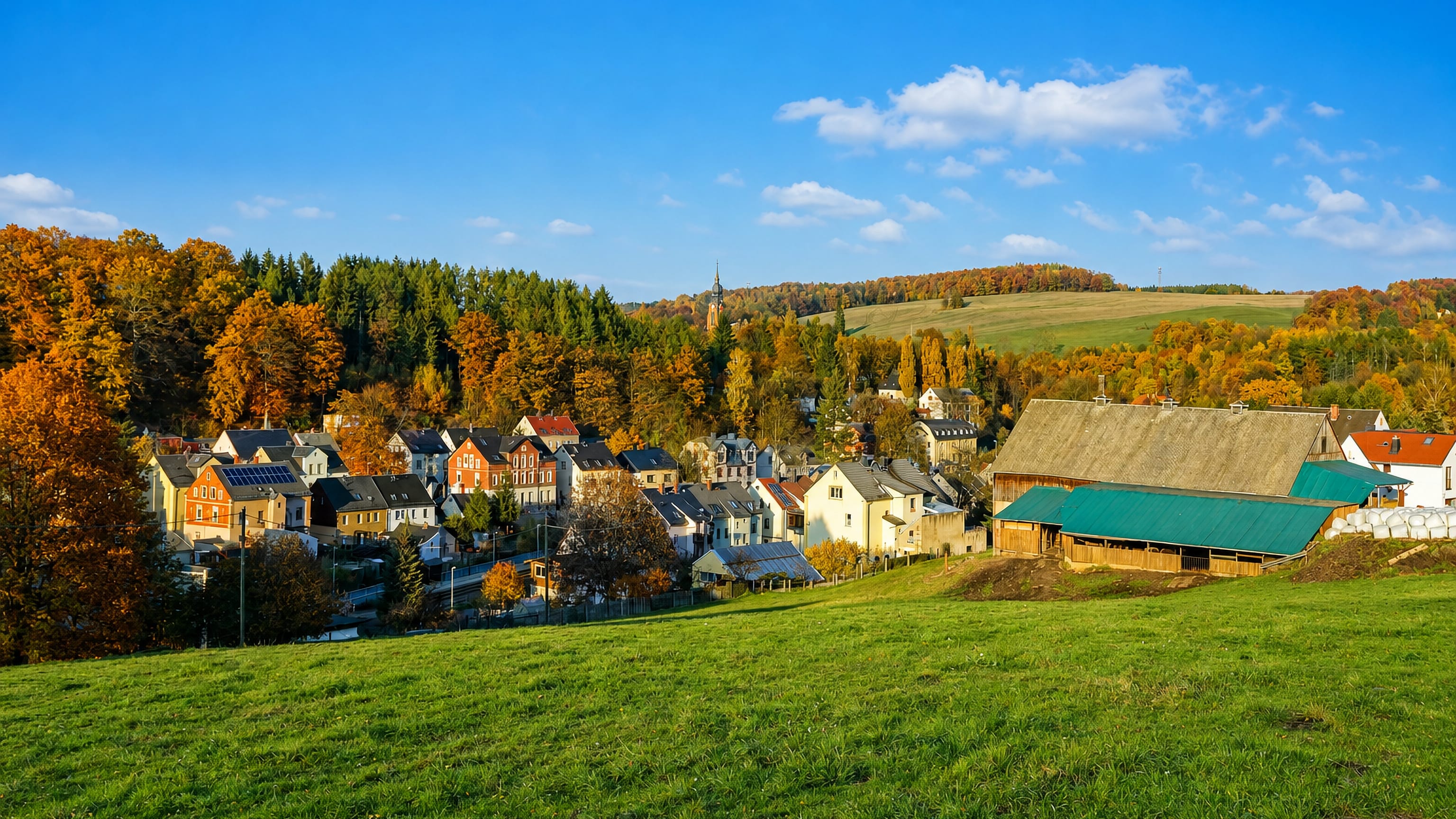Autumn hillside view over the houses and church tower of Harthau in the valley south of Chemnitz.