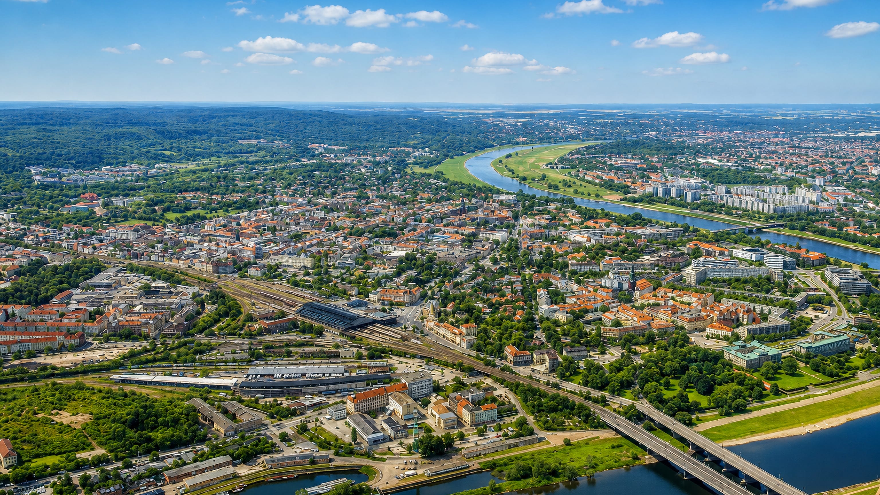 Aerial view over Dresden's Äußere Neustadt, its railway station and rooftops beside a bend in the Elbe.