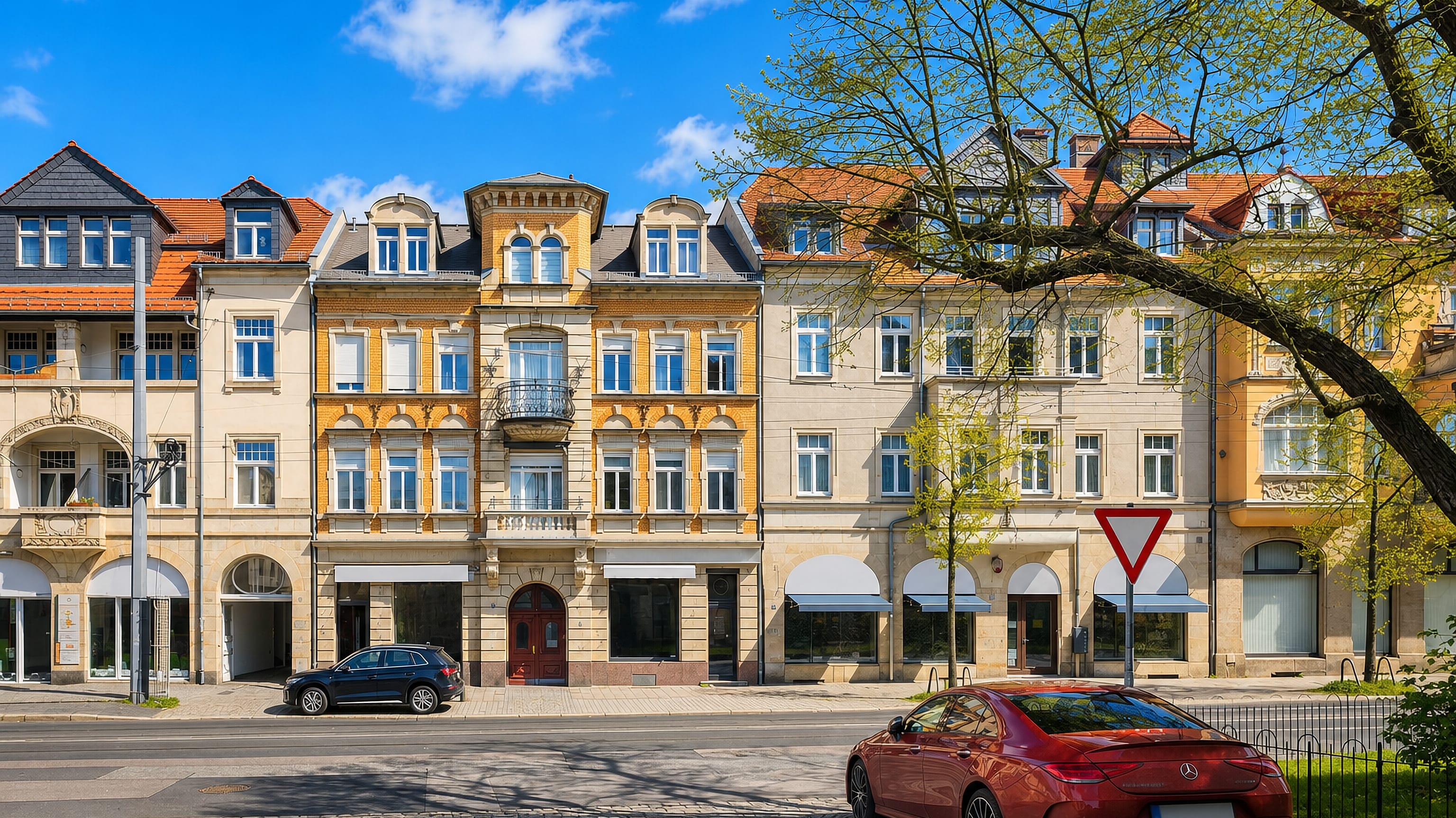 Ornate Gründerzeit facades and shopfronts along a sunlit street in Dresden's Weisser Hirsch.