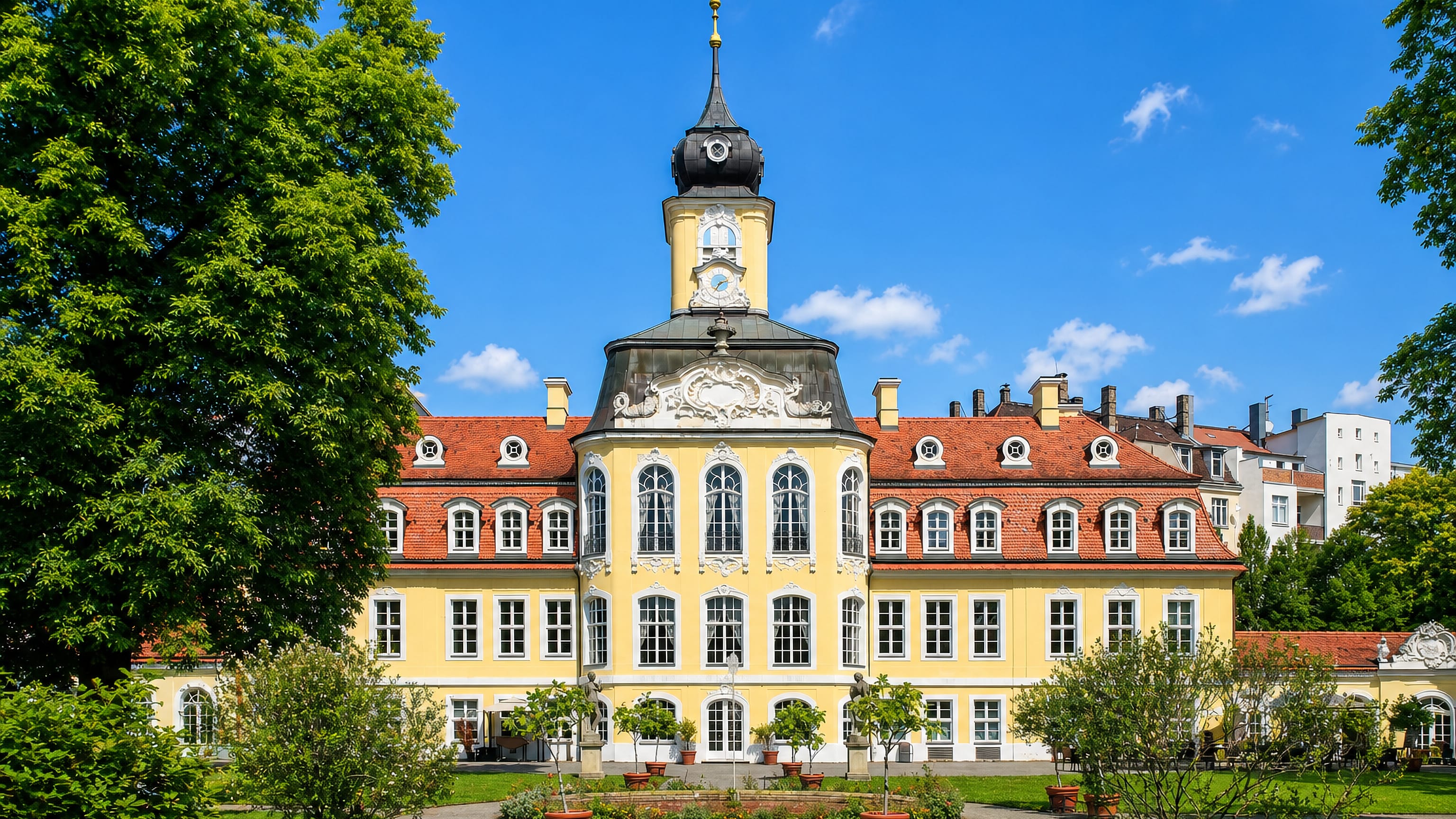 Yellow rococo palace with a domed clock tower and formal garden in Gohlis, Leipzig.