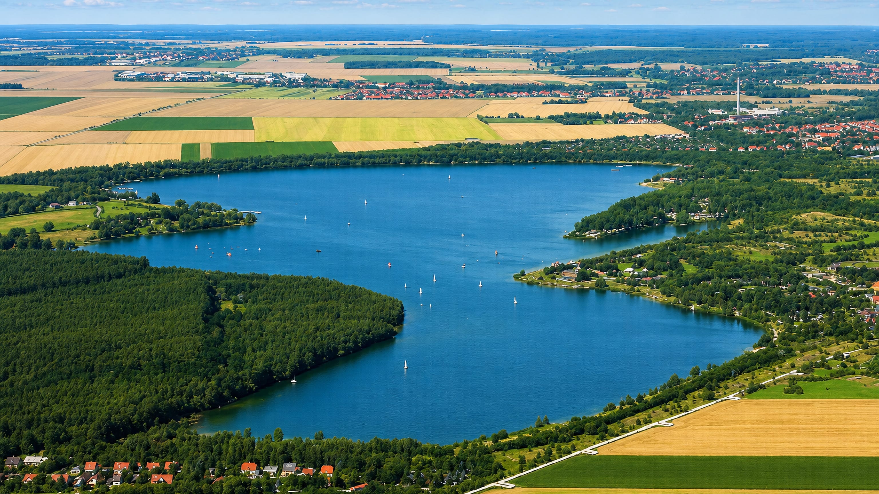 Sailing boats on the Kulkwitzer See beside Grünau in Leipzig, ringed by woodland and open farmland