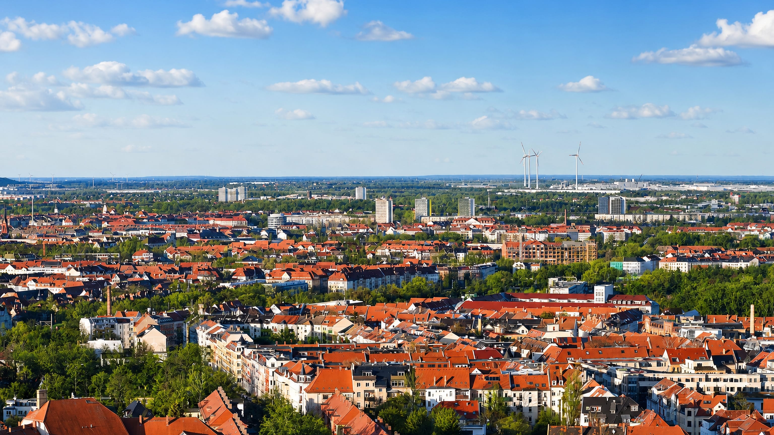 Red-tiled rooftops of Stötteritz stretching across Leipzig to wind turbines on the horizon.