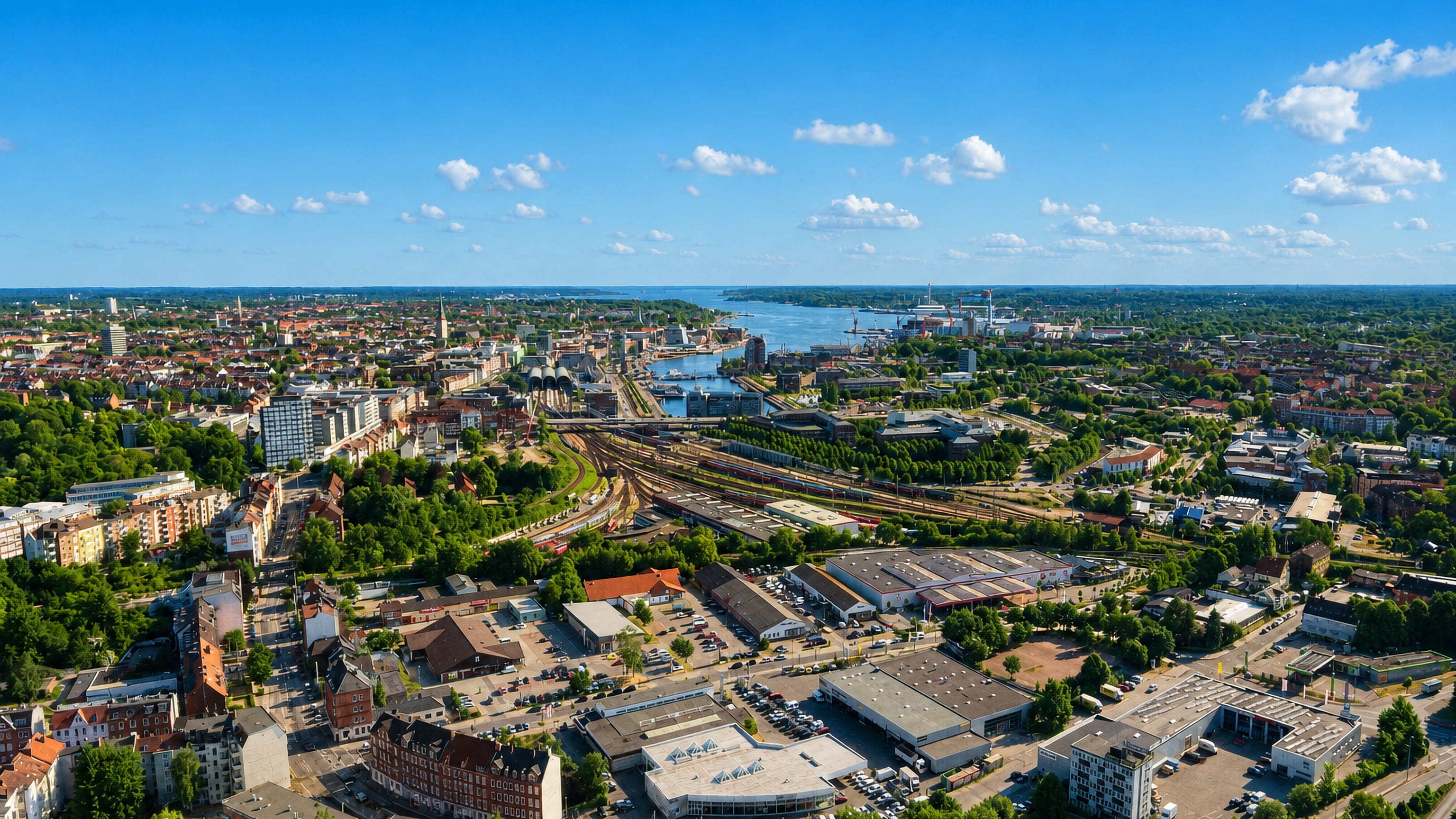 Aerial view over Kiel Altstadt, its harbour and rail yards, with the Kiel Fjord opening to the Baltic.