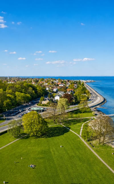 Aerial of Charlottenlund's coastal park, shoreline road and harbour pavilion on the Øresund