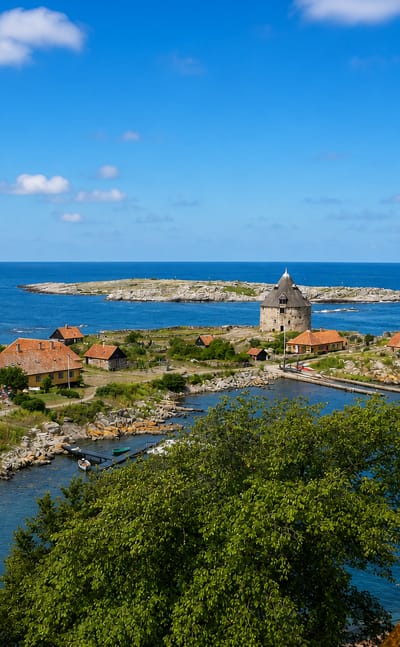 The fortified islet of Christiansoe in Denmark's Ertholmene, with its round stone tower and red-roofed houses ringed by sea.