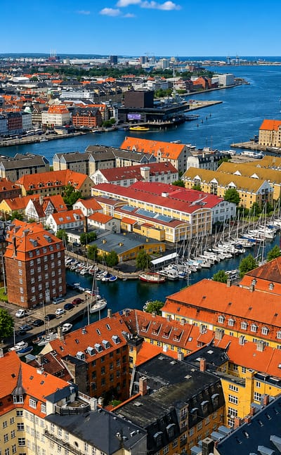 Aerial view over Christianshavn, Copenhagen, with its boat-lined canal, colourful red-roofed houses and the harbour Opera House beyond.