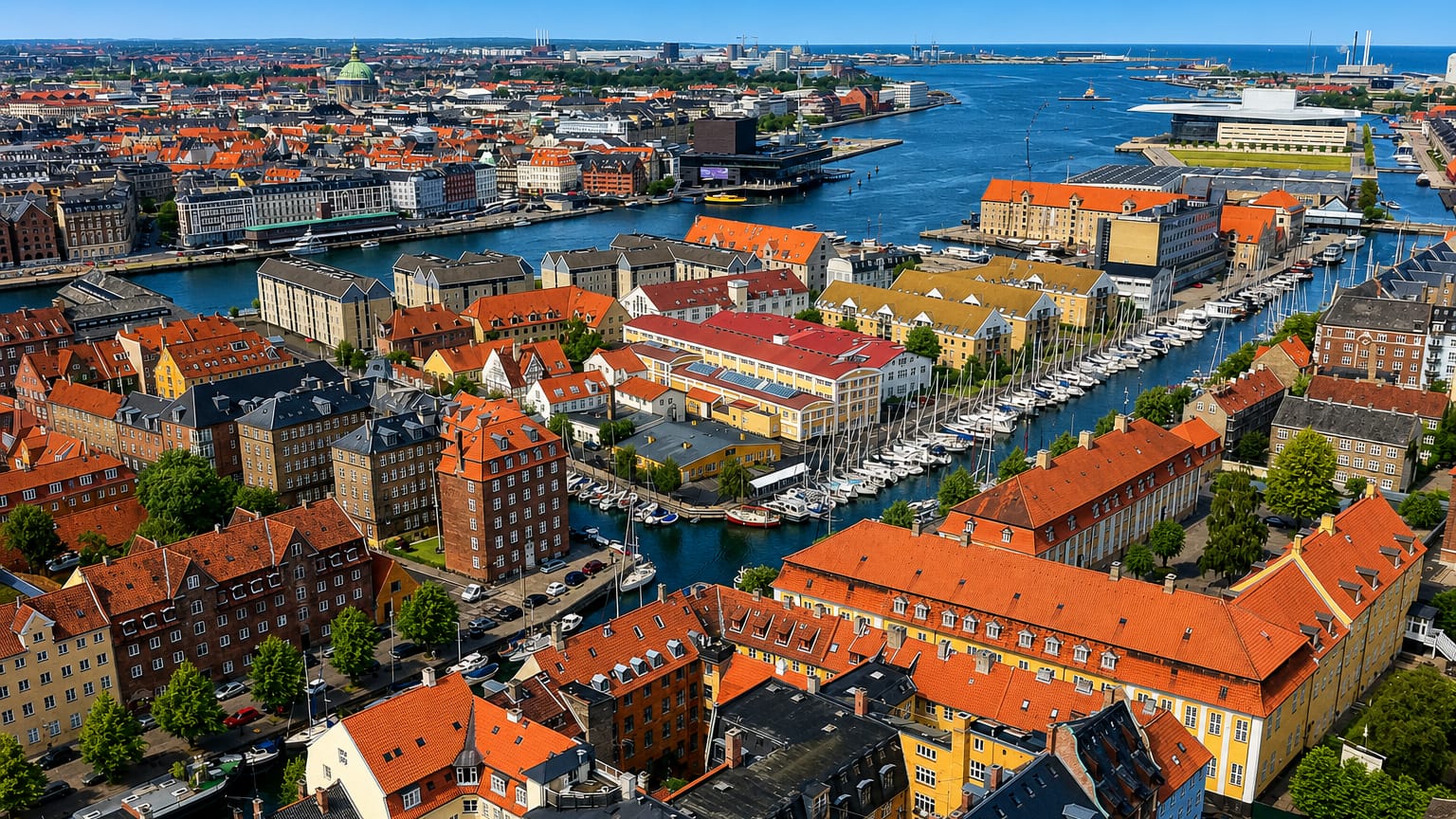 Aerial view over Christianshavn, Copenhagen, with its boat-lined canal, colourful red-roofed houses and the harbour Opera House beyond.