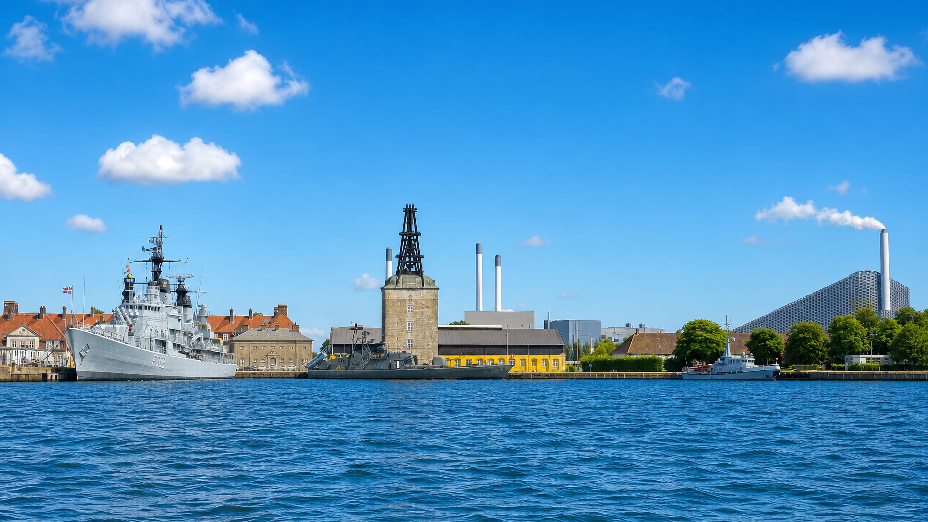 Holmen in Copenhagen across the harbour: the Nyholm mast crane, yellow naval sheds and a moored warship