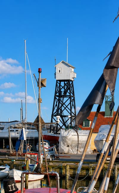 Dragor harbour in Denmark with the black timber lookout tower, moored boats and fishing flags