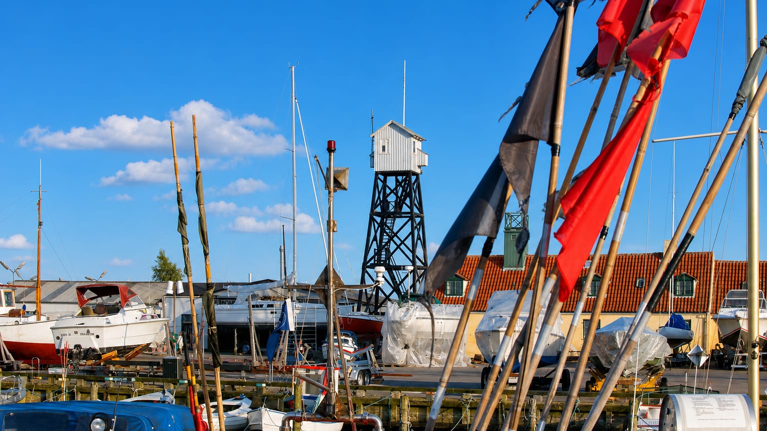 Dragor harbour in Denmark with the black timber lookout tower, moored boats and fishing flags