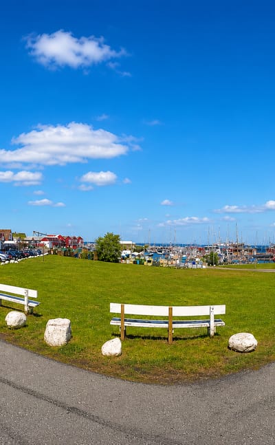 Waterfront green with an anchor monument and benches beside Gilleleje harbour and marina, Denmark