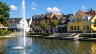 Helsinge town square with a fountain pond and colourful shopfront townhouses in North Zealand, Denmark.